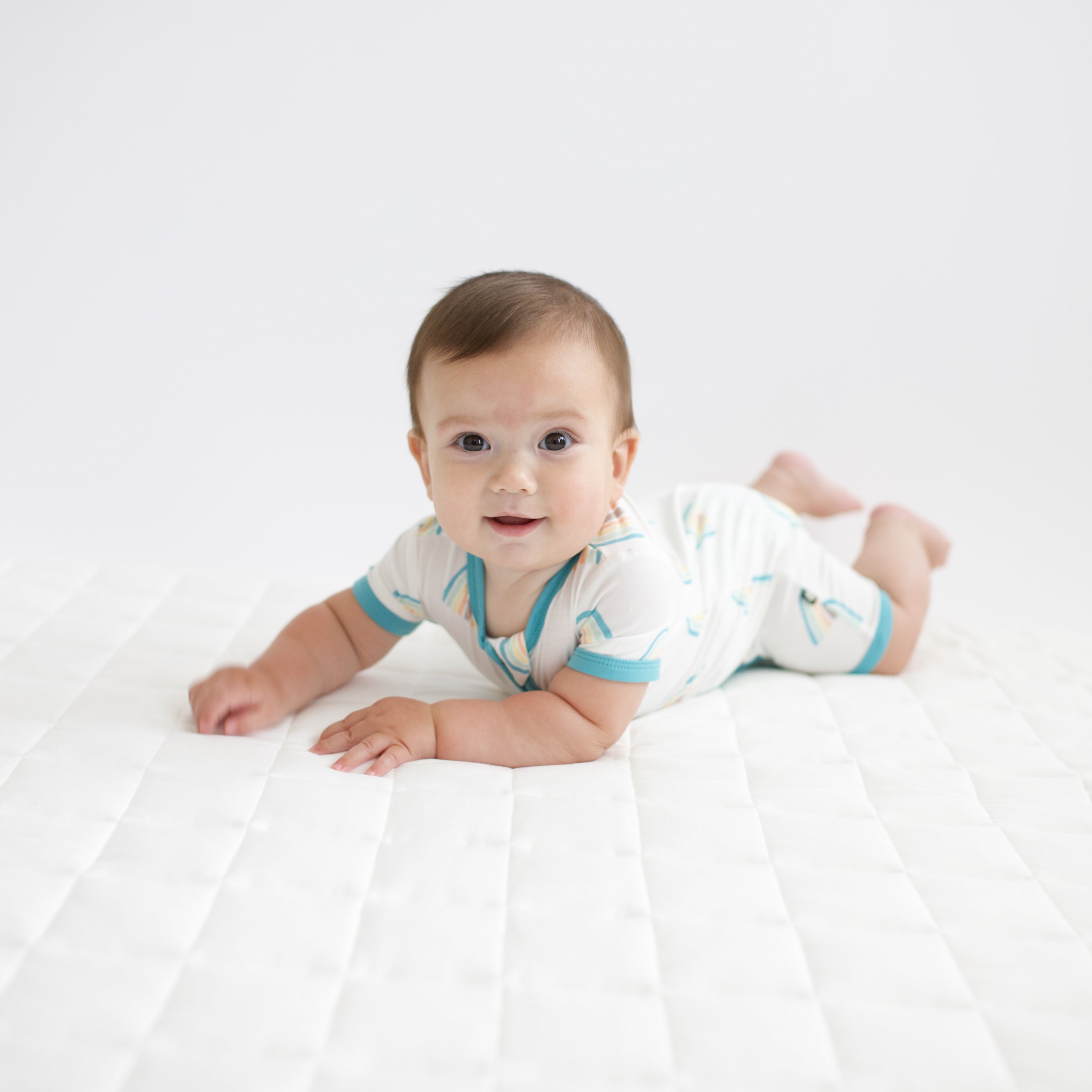 Infant wearing bamboo Kyte Baby Zippered Shortall Romper in Makai Rainbow