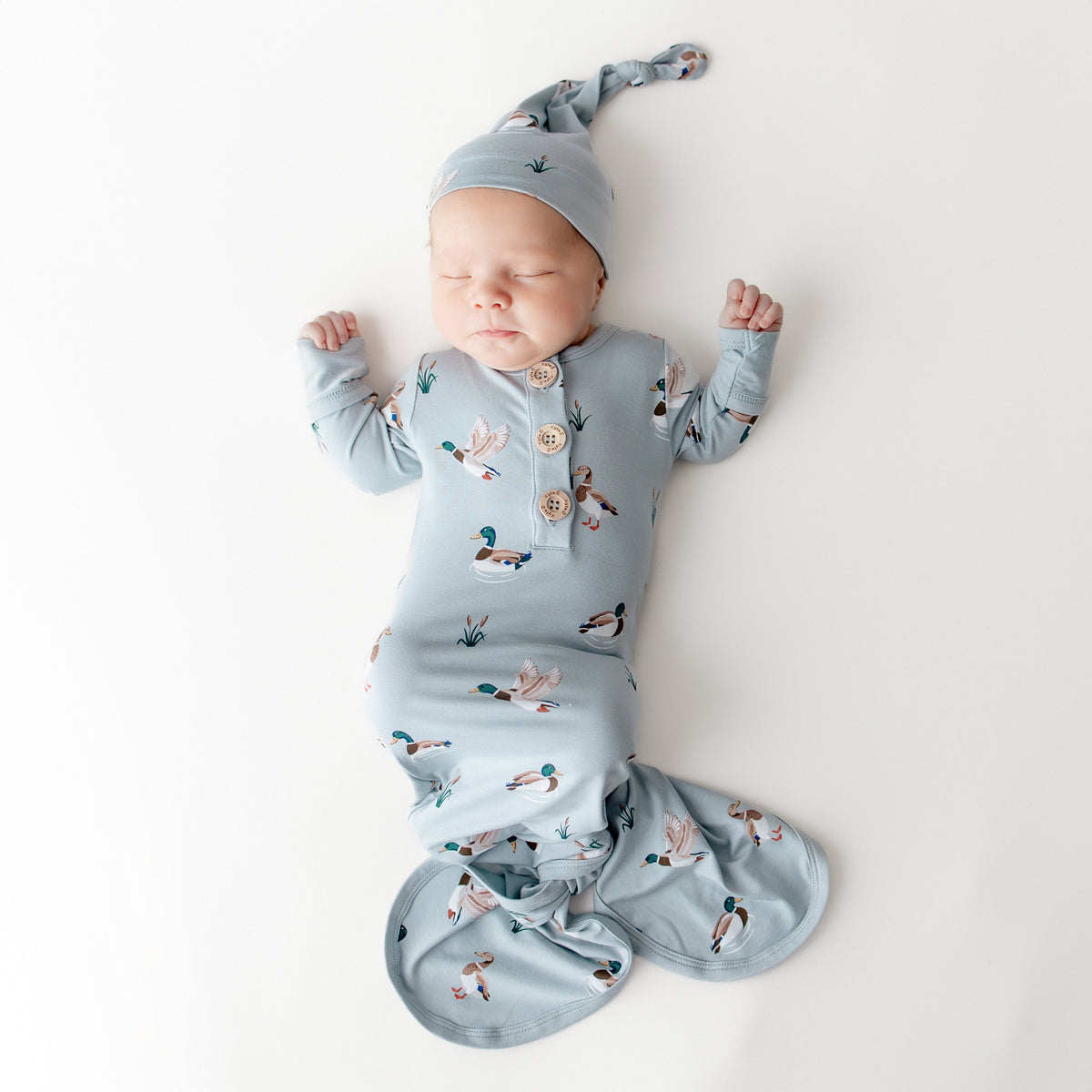 Sleeping newborn wearing the Knotted Gown with Hat Set in Mallard Duck