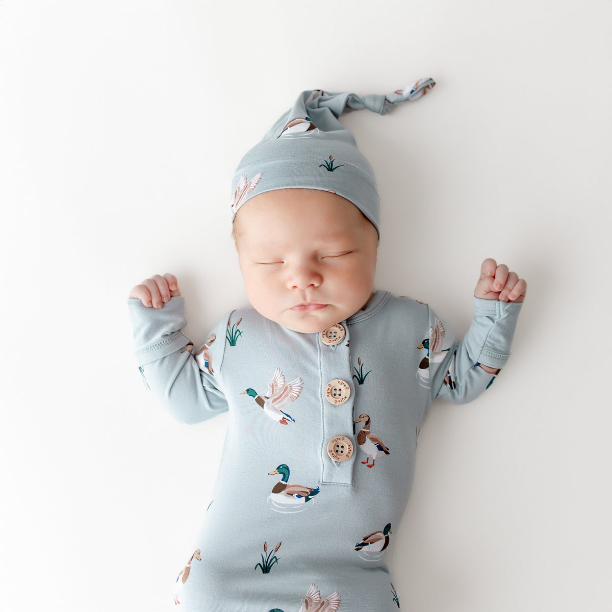 Close up of sleeping newborn wearing the Knotted Gown with Hat Set in Mallard Duck