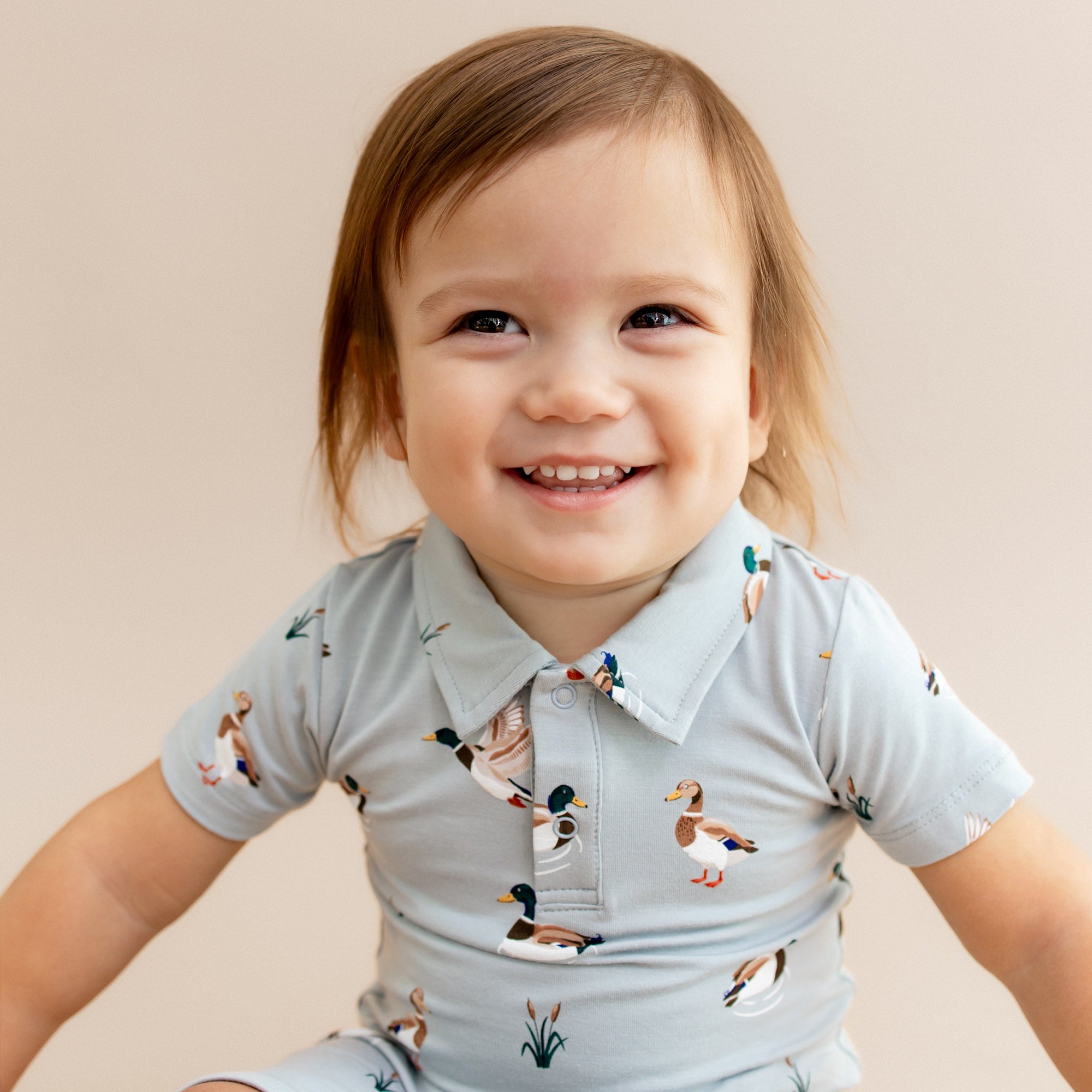 Close up of smiling toddler wearing the Polo Shortall in Mallard Duck