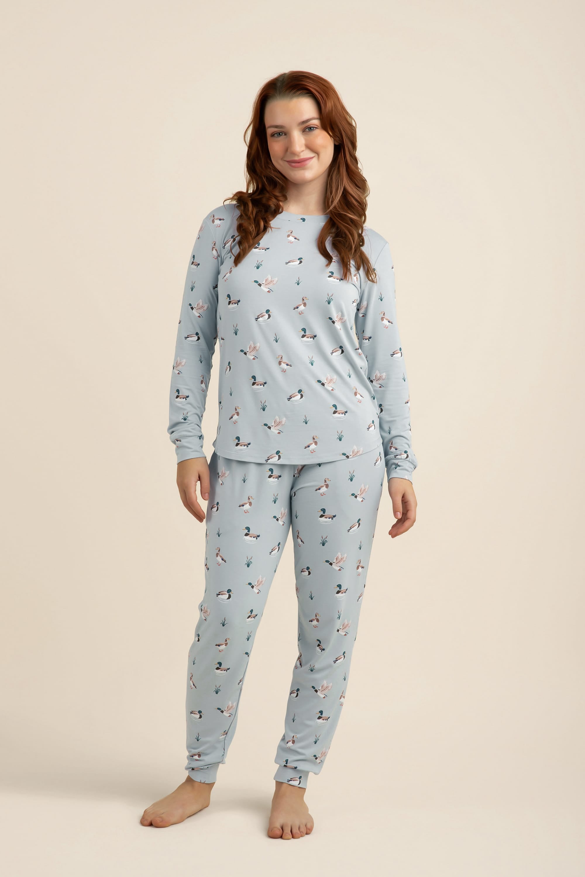 Woman wearing a light blue pajama set with a duck pattern on a beige background