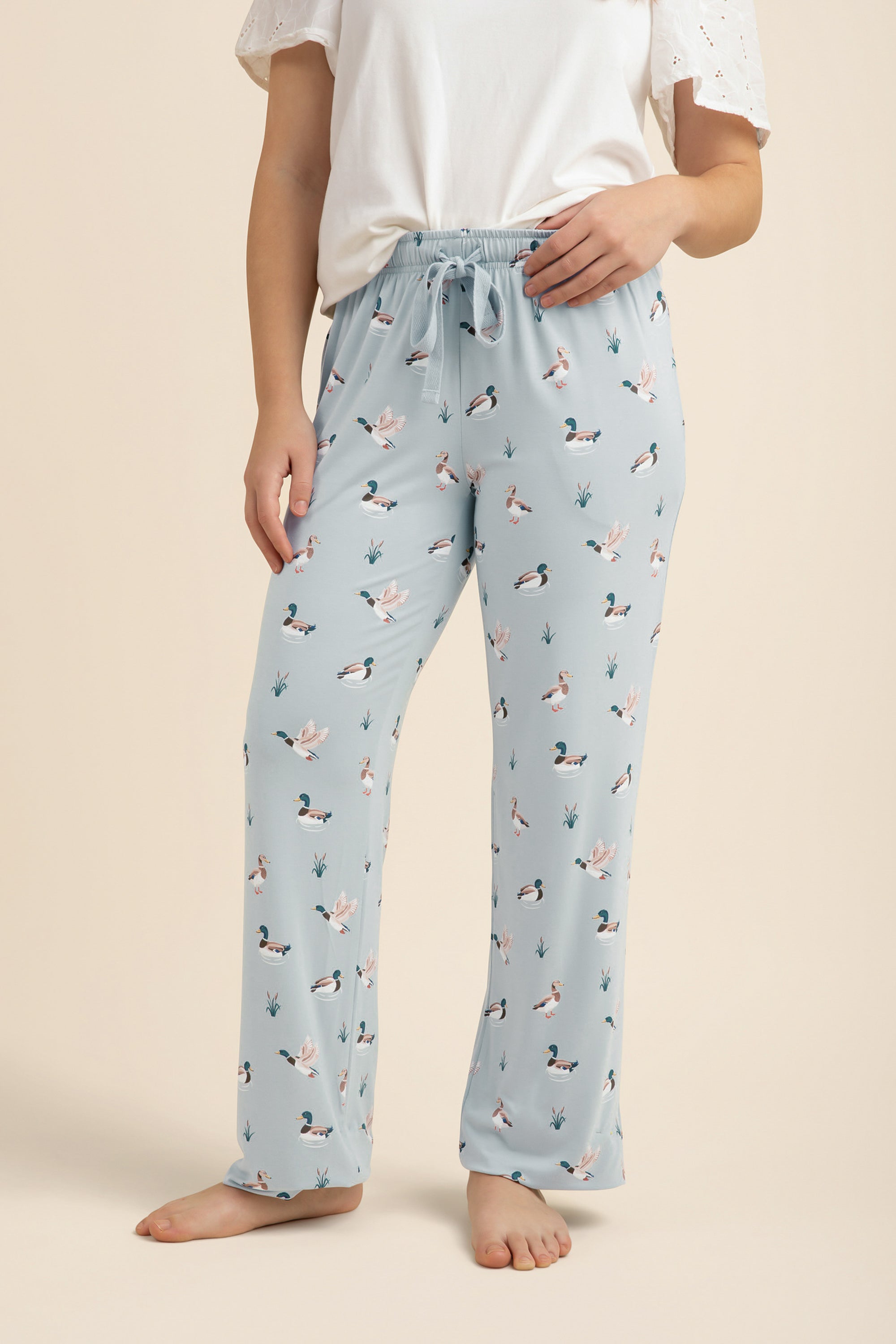 Light blue lounge pants with duck pattern worn by a person on a beige background