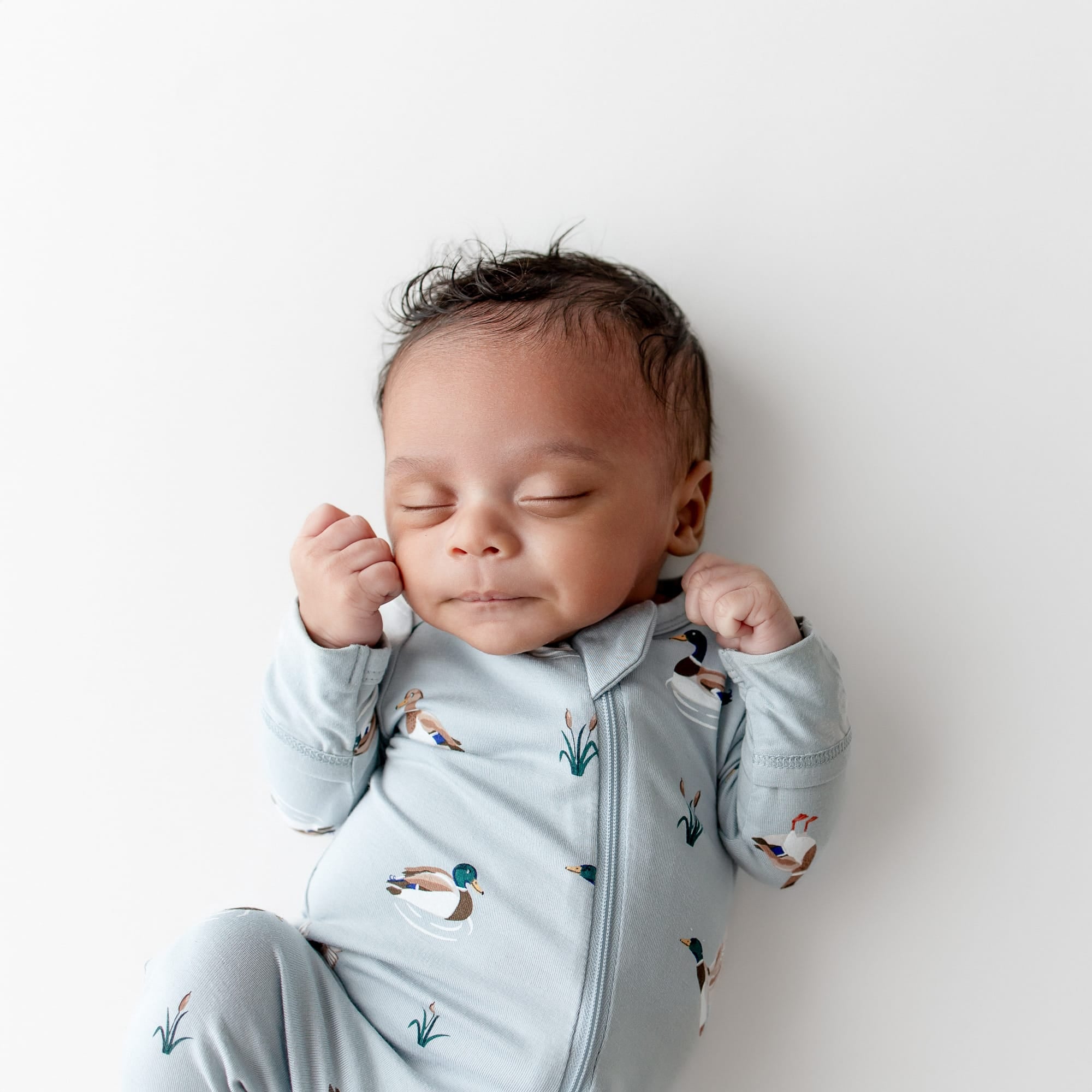 Close up of sleeping newborn wearing the Zippered Footie in Mallard Duck