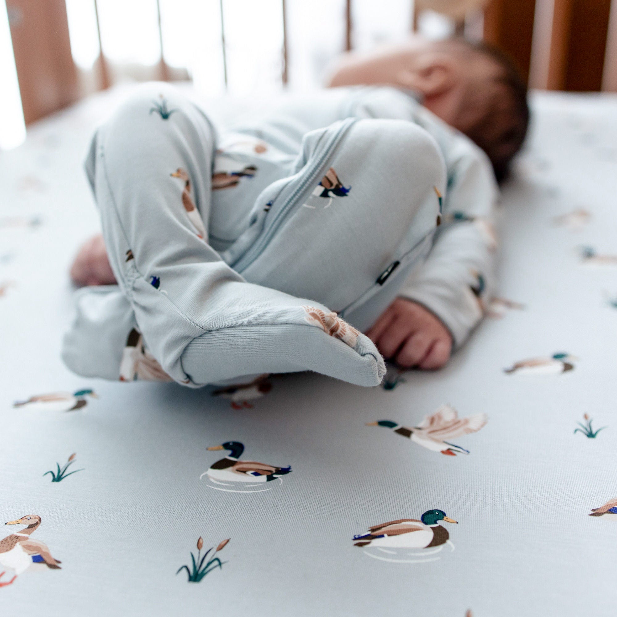 Close up of the foot pads on the Zippered Footie in Mallard Duck shown on a newborn laying in a crib on a Mallard Duck Crib Sheet