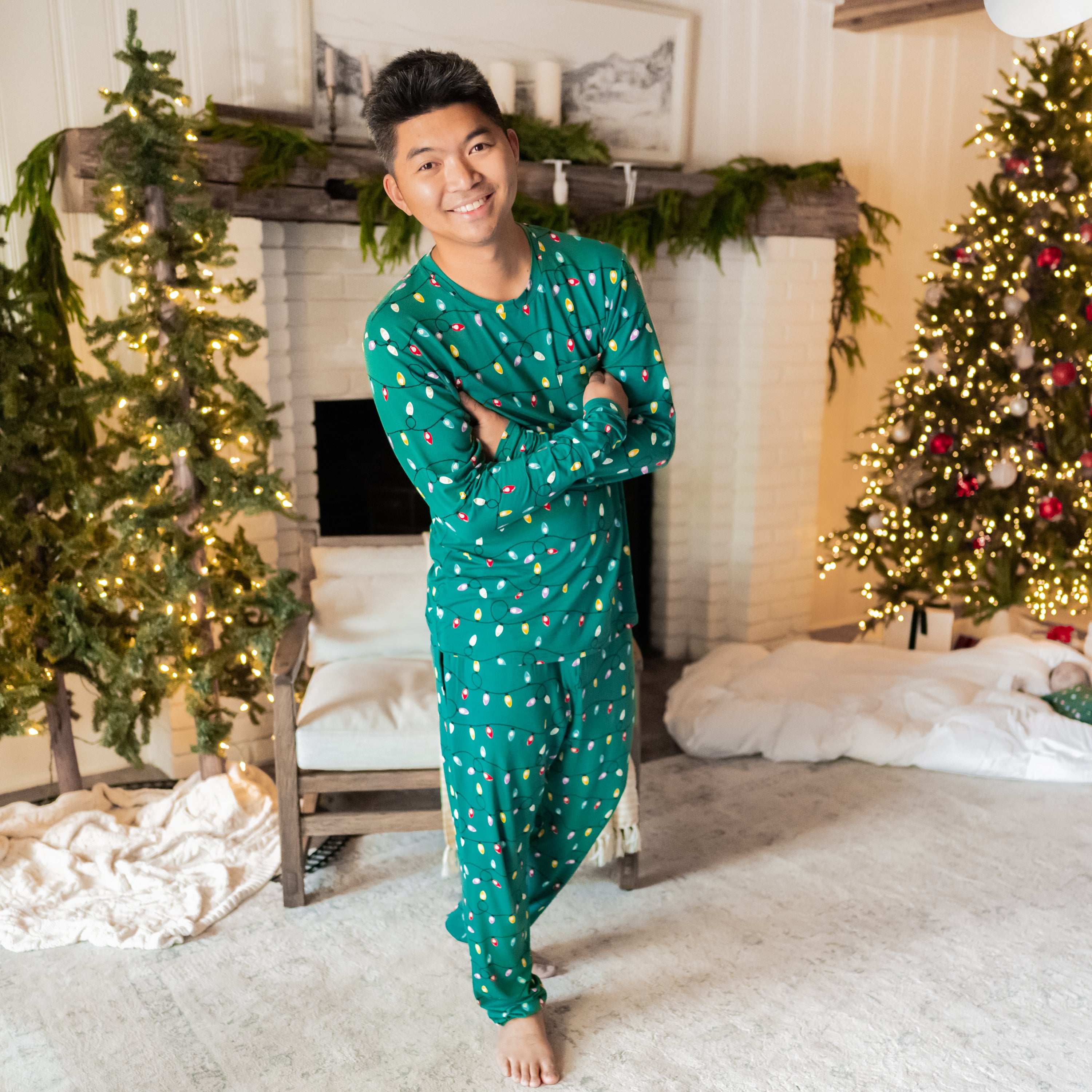 Male standing with his arms crossed in front of a white brick fireplace and decorated Christmas trees wearing the Men's Jogger Set in Merry and Bright