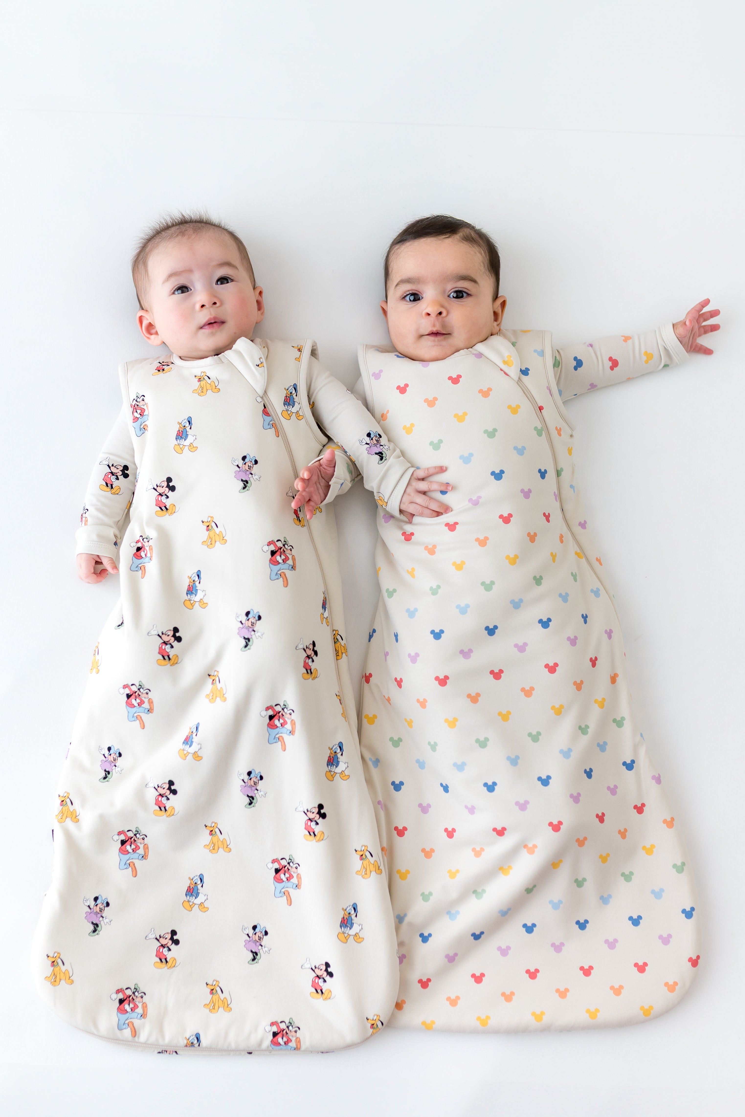 2 babies wearing sleep sacks in mickey mouse patterns