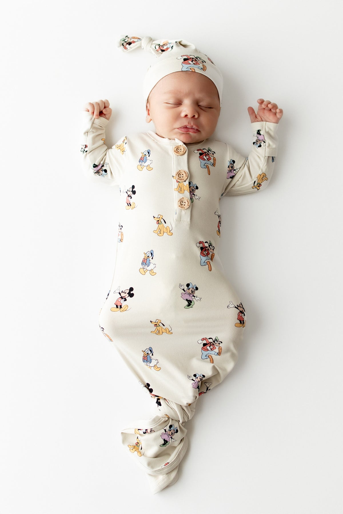 Baby asleep in a mickey character pattern gown with matching cap