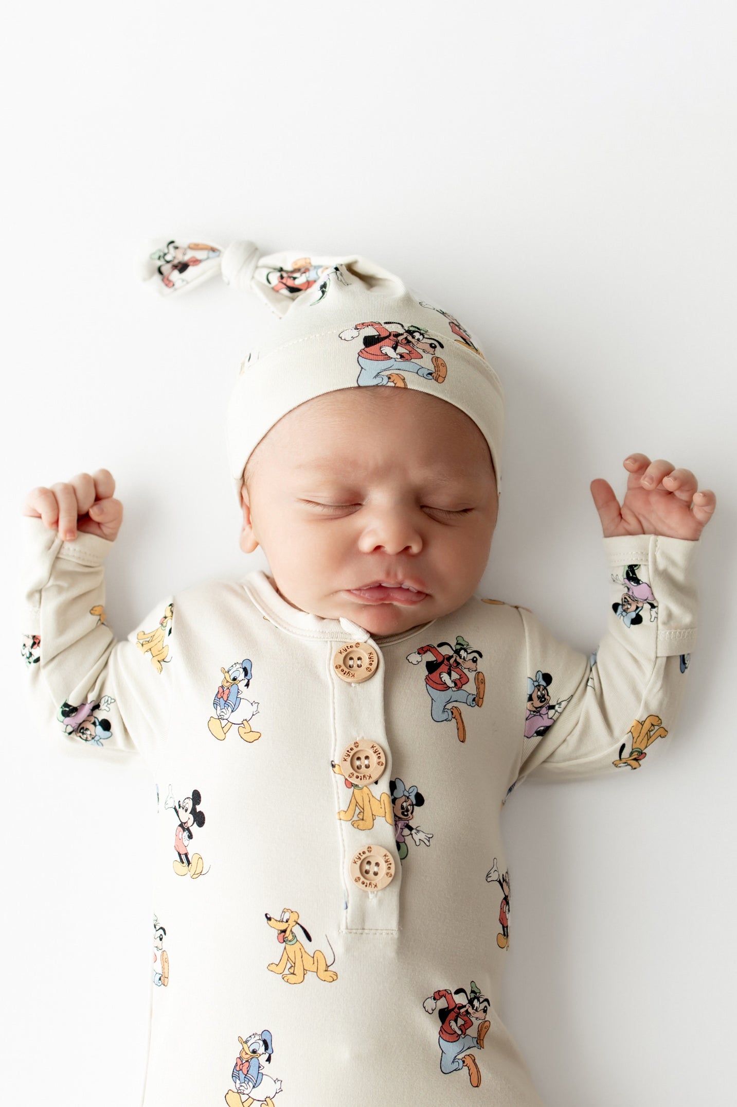 Baby wearing knotted cap and gown with buttons in a mickey and friends pattern