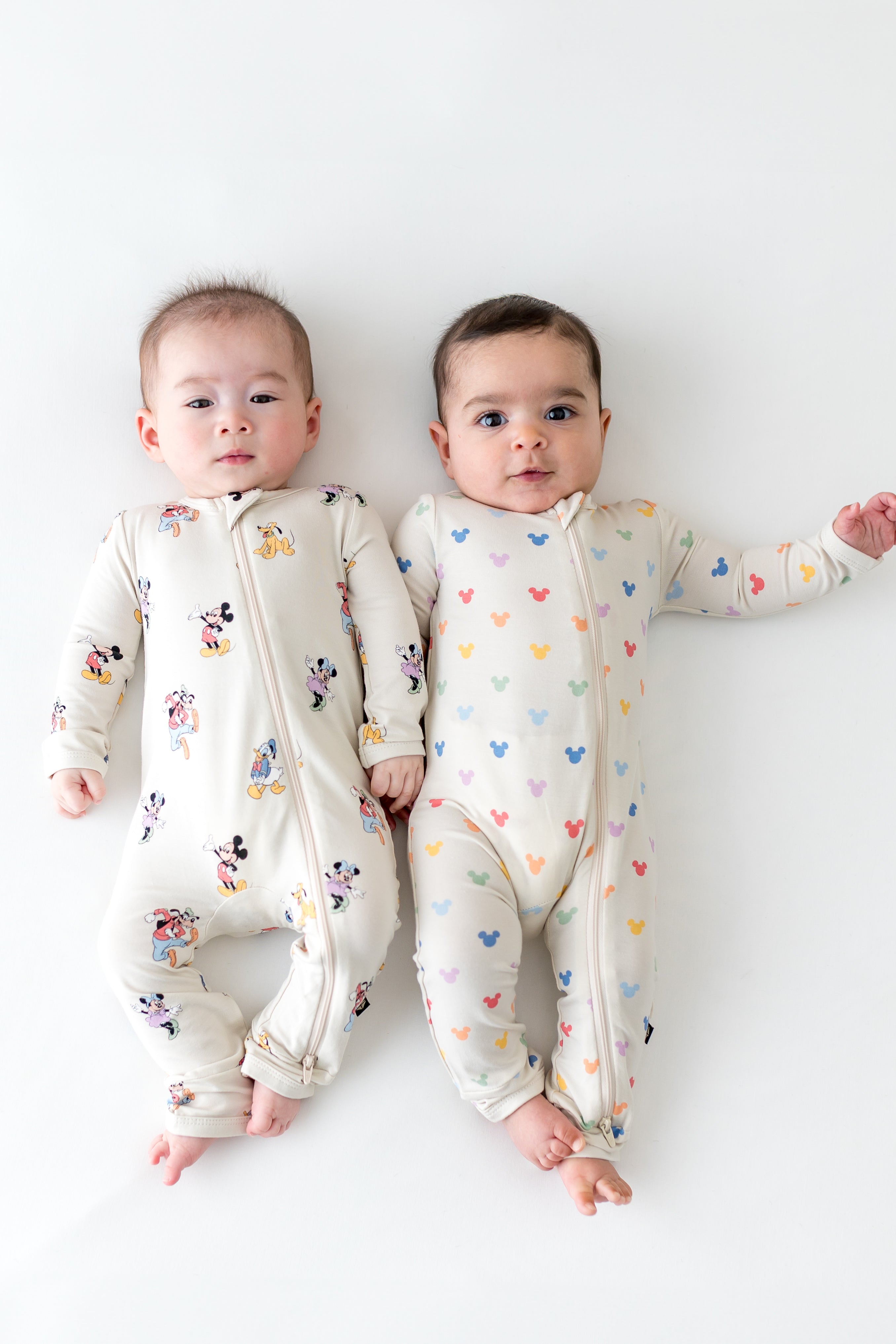 2 babies wearing zippered rompers in mickey mouse patterns