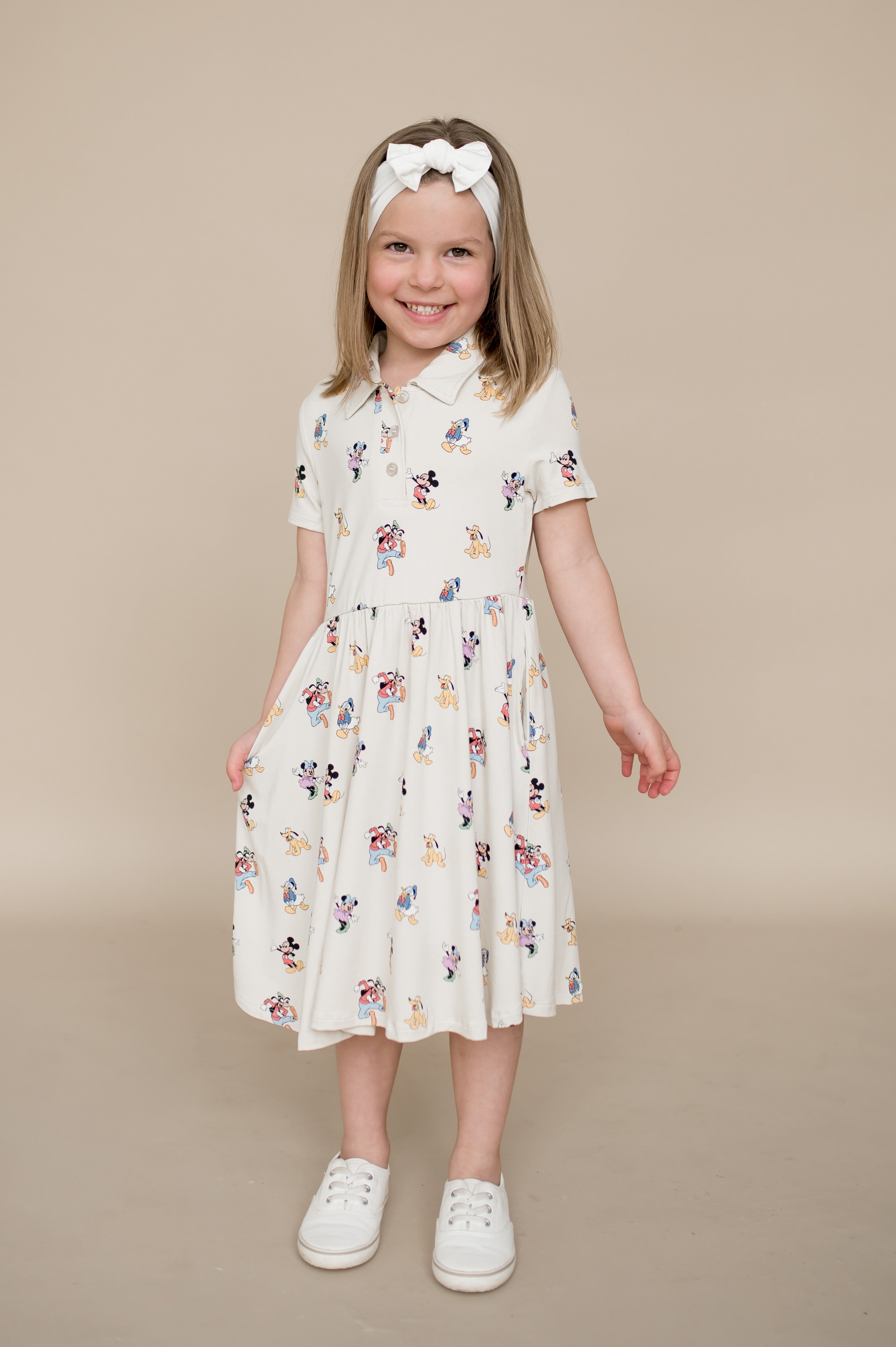 Young girl wearing a mickey character dress on a beige background