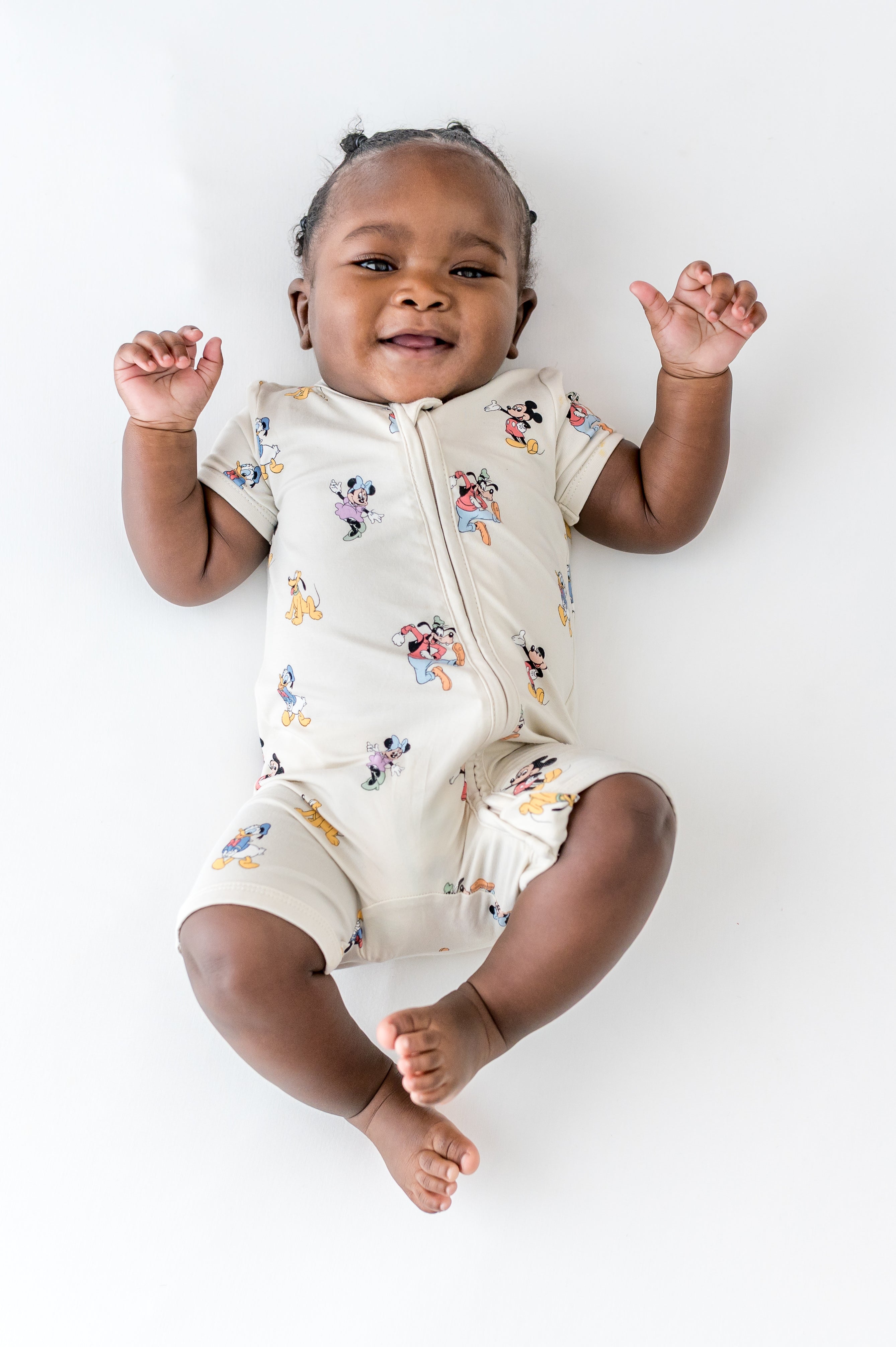 Baby in zipper shortall in a mickey and friends pattern