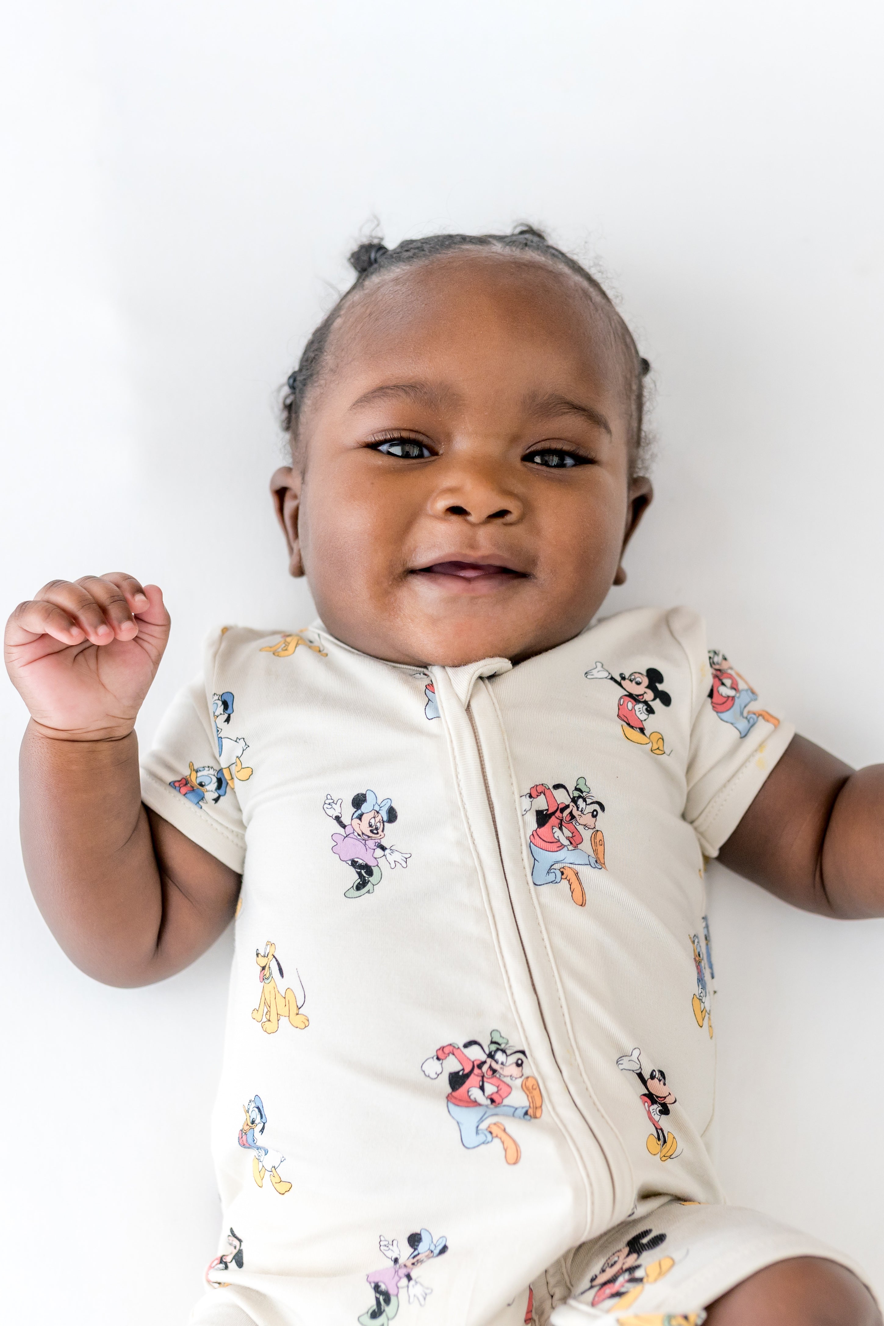 Baby in a zippered shortall style with a mickey and friend pattern