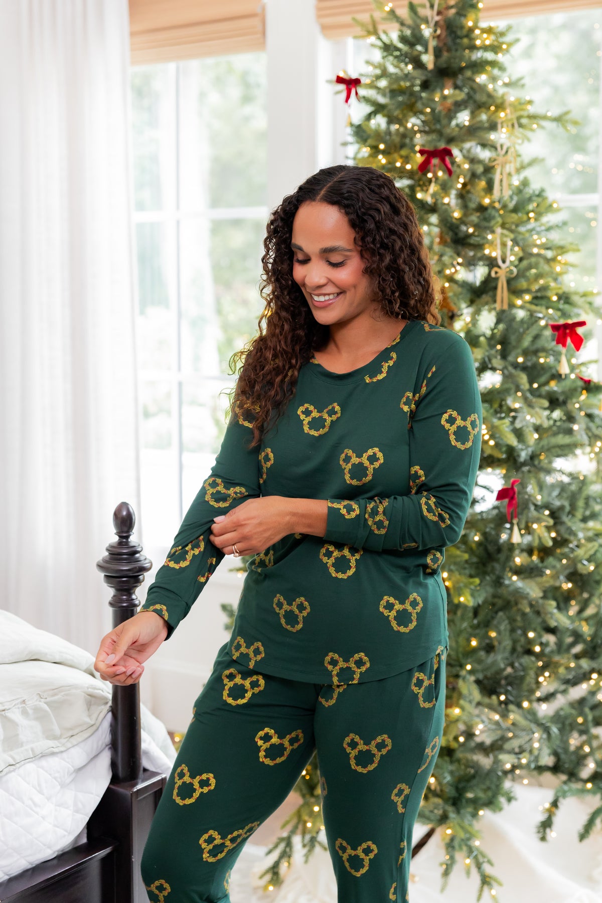 Woman wearing Women's Jogger Pajama Set in Mickey Christmas Wreath print posing in front of Christmas tree