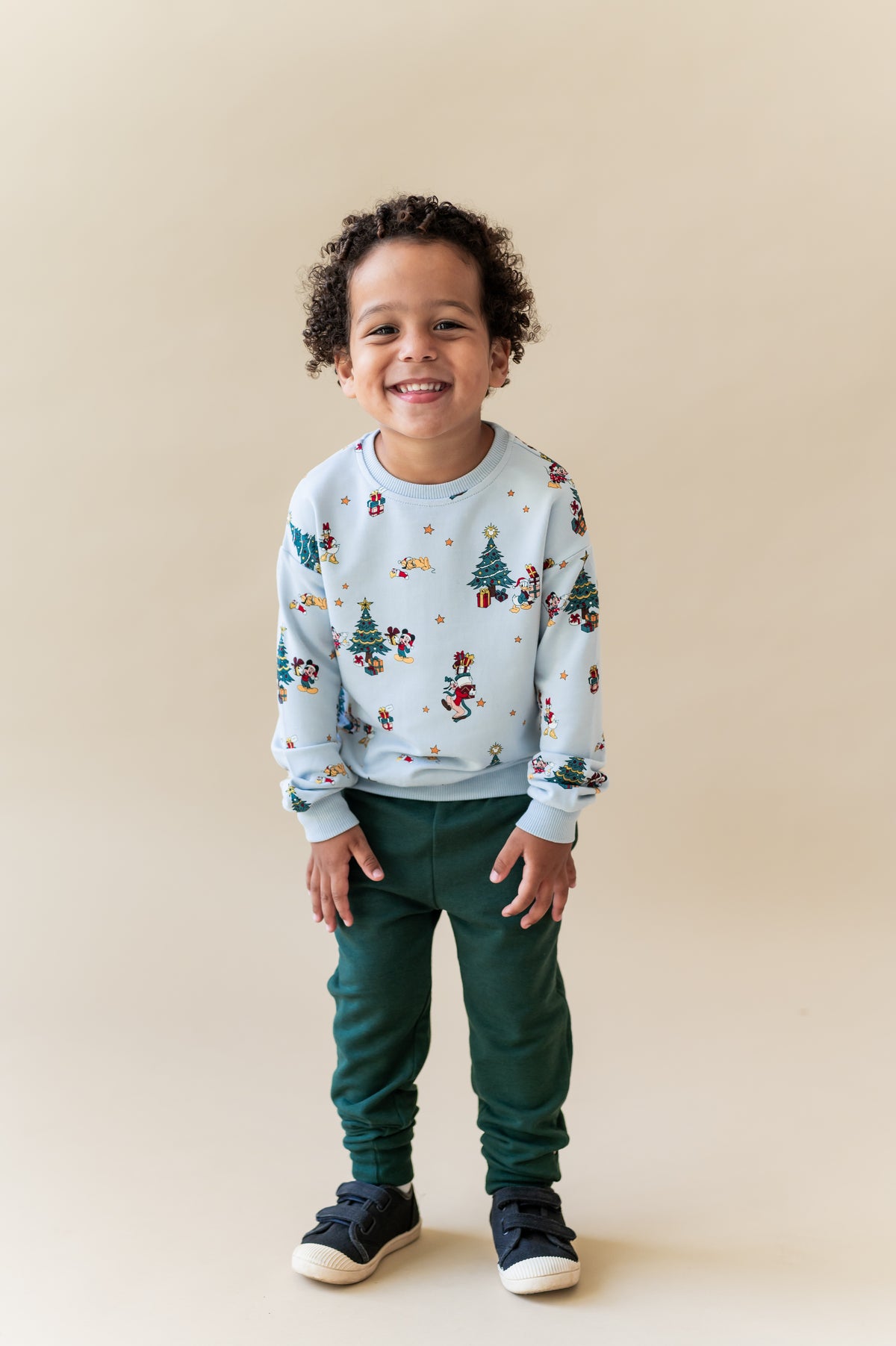 Boy smiling in Sweatshirt in Mickey & Friends Christmas print over green pants