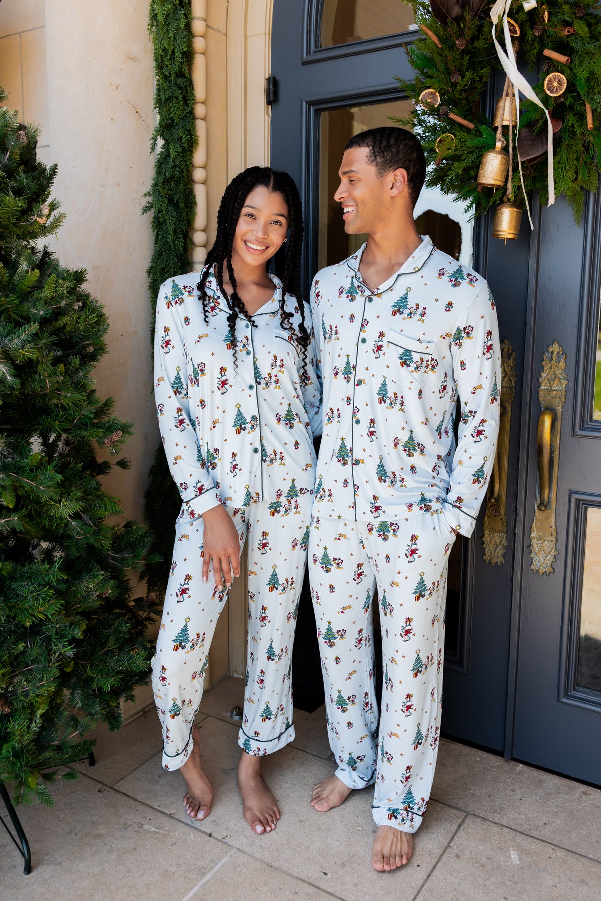 Man and woman wearing Long-Sleeved Pajama Set in Mickey & Friends Christmas print standing outdoors