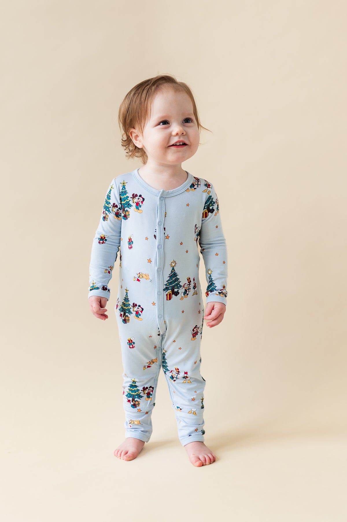 Toddler wearing Romper in Mickey & Friends Christmas print with snap buttons on a beige background