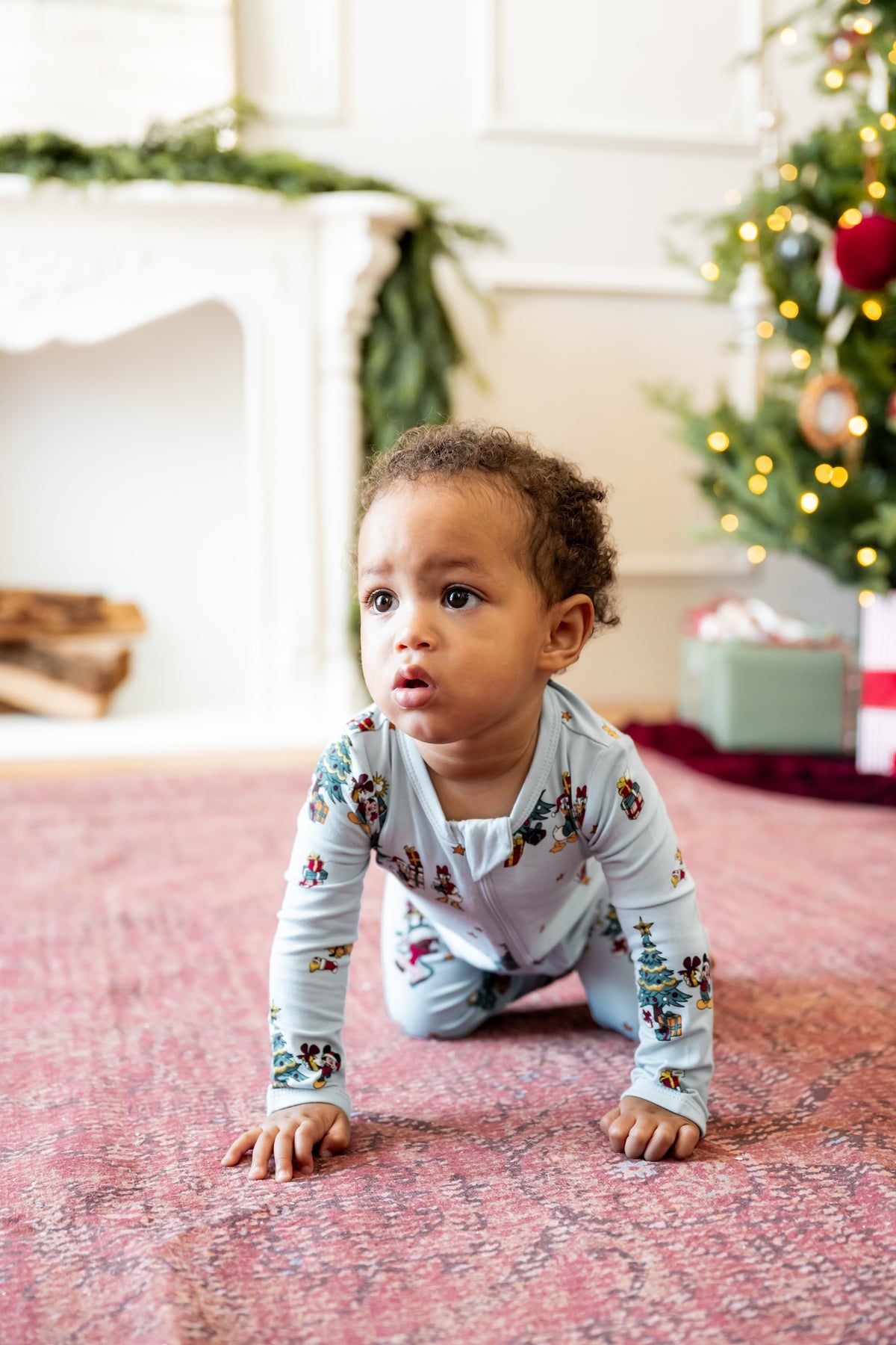 Boy crawling in front of Christmas Tree and presents wearing Zippered Romper in Mickey & Friends Christmas print