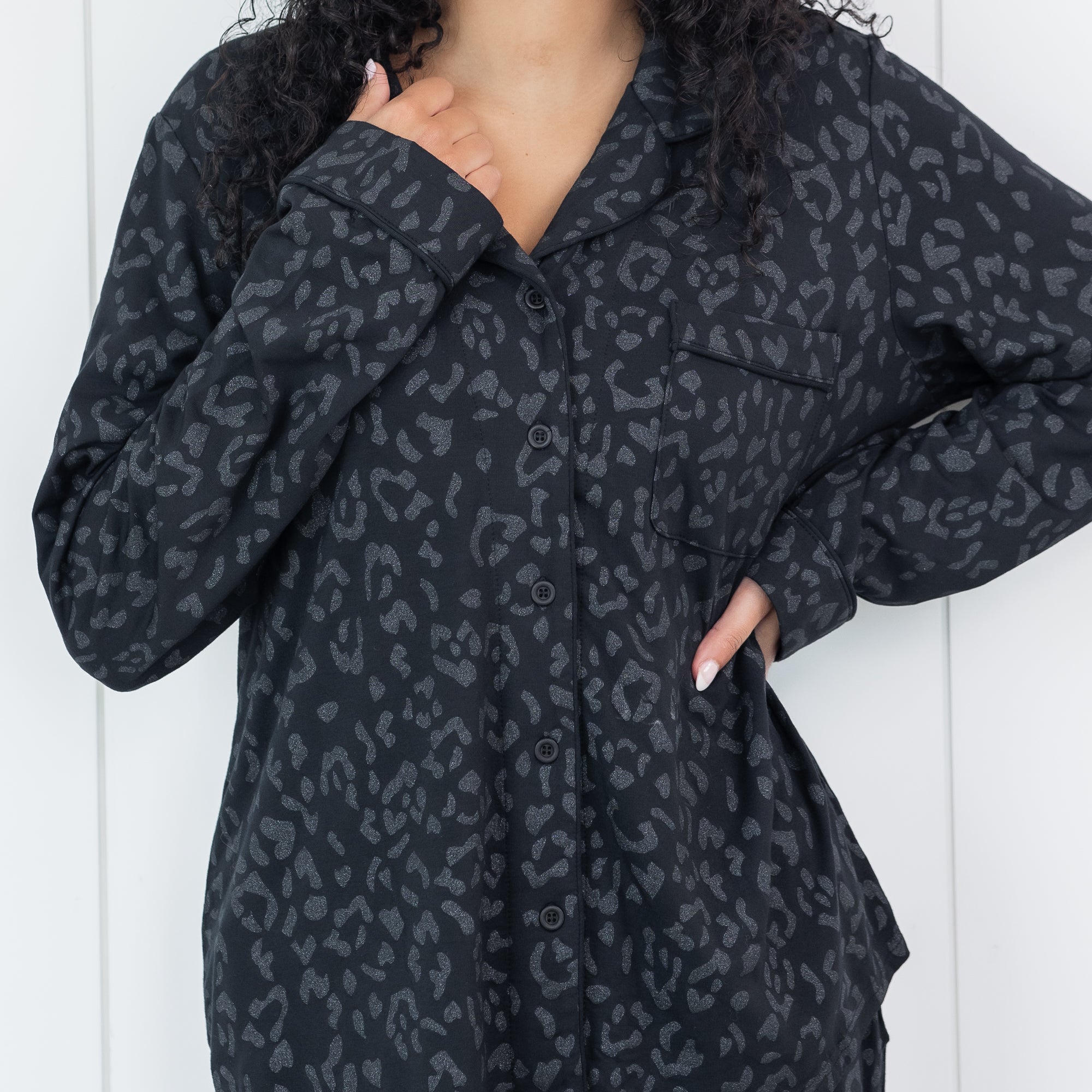 Person wearing a black leopard patterned pajama shirt against a white background