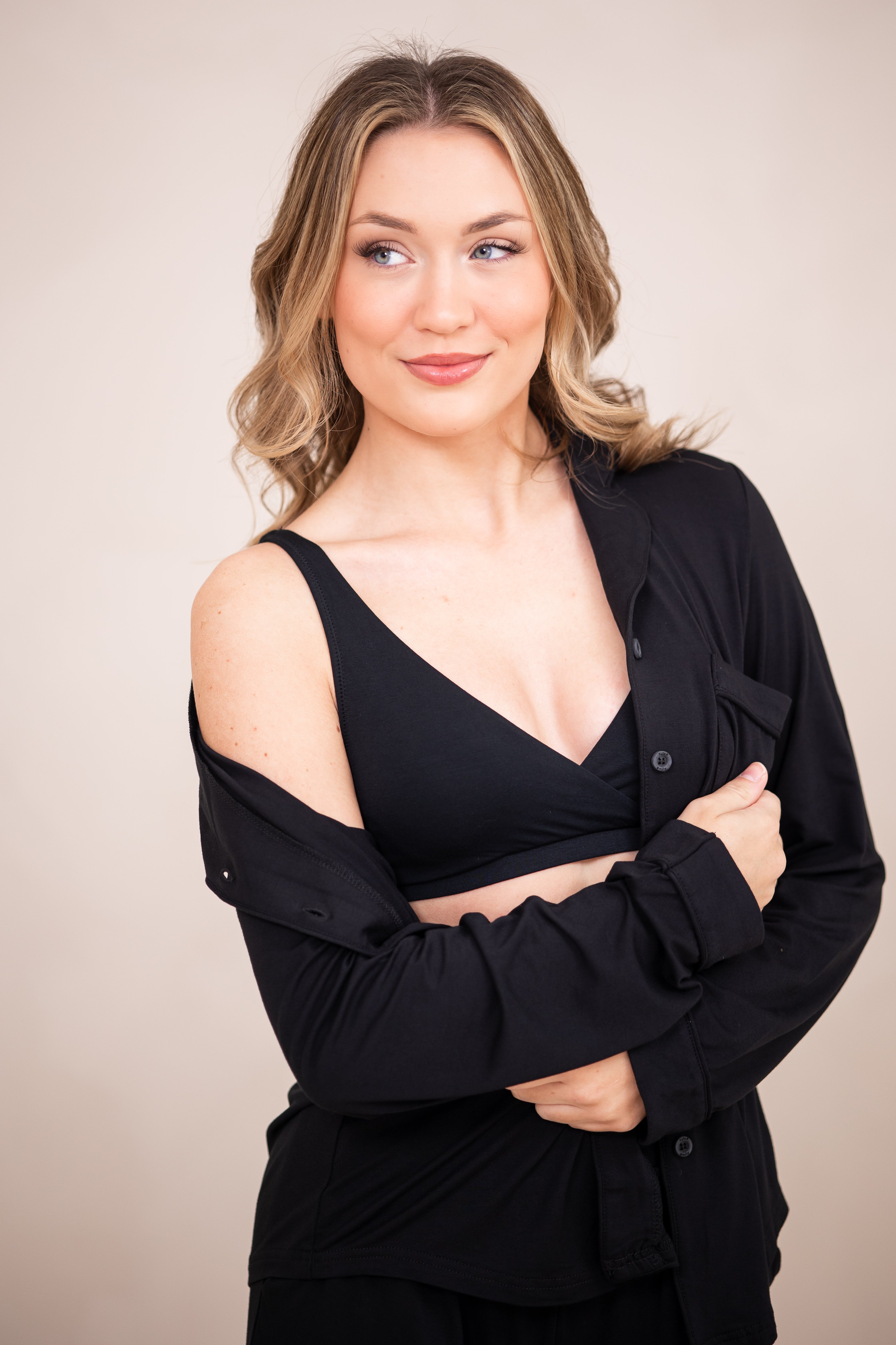 Woman in black cross front bralette with unbuttoned pajama top