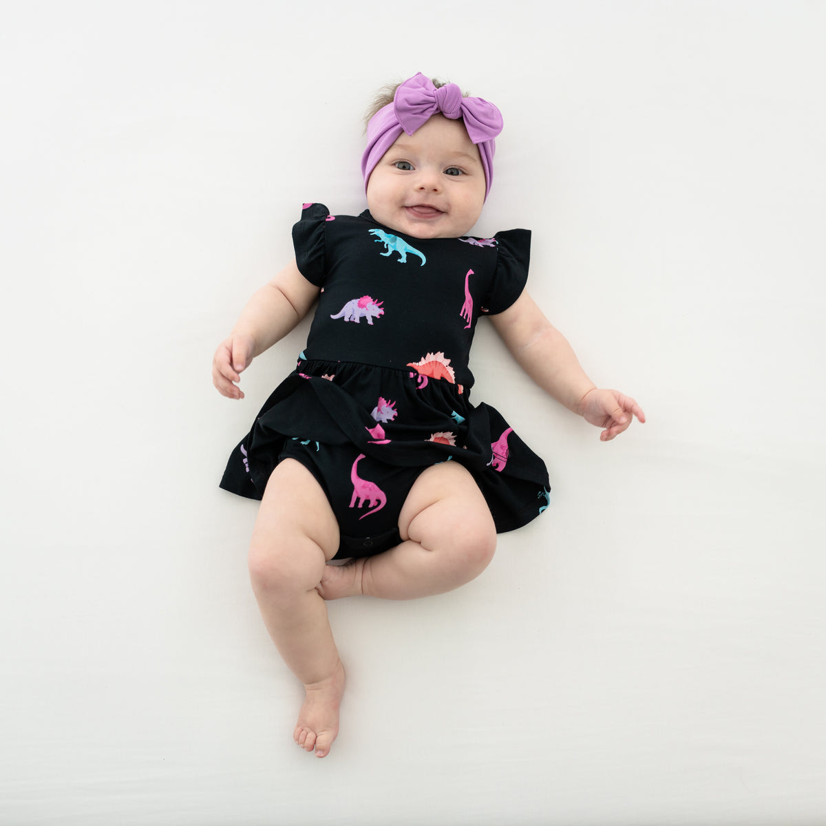 Infant model in Midnight Roar Short Sleeve Twirl Bodysuit Dress paired with a Poi bow