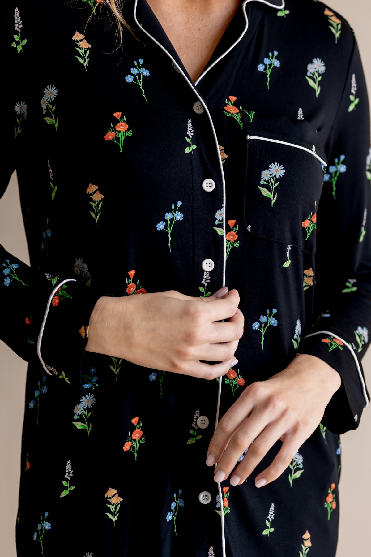 Model showcasing the front white buttons of Long Sleeve Women’s Nightshirt in Midnight Wildflower print on a beige background