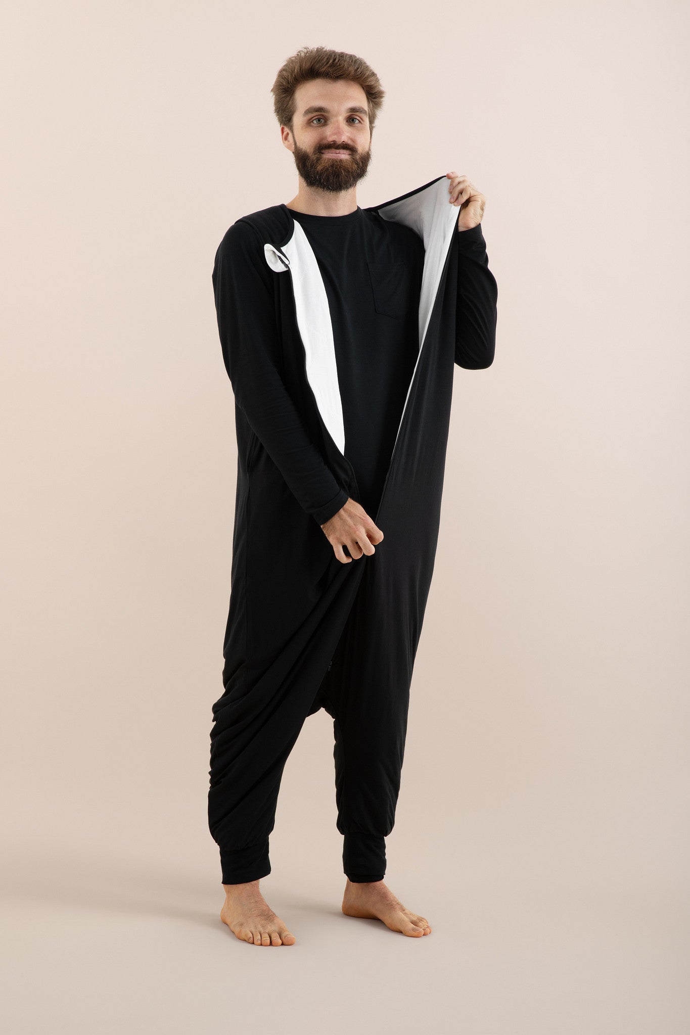 Male model wearing the Adult Sleep Bag Walker in Midnight unzipping it