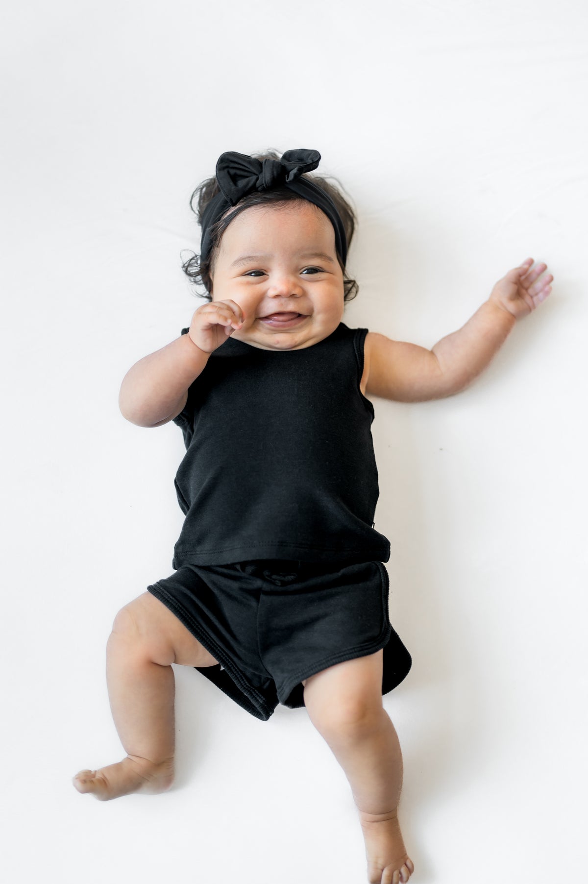 Smiling infant laying on a white surface wearing the Tank Jogger Set in Midnight