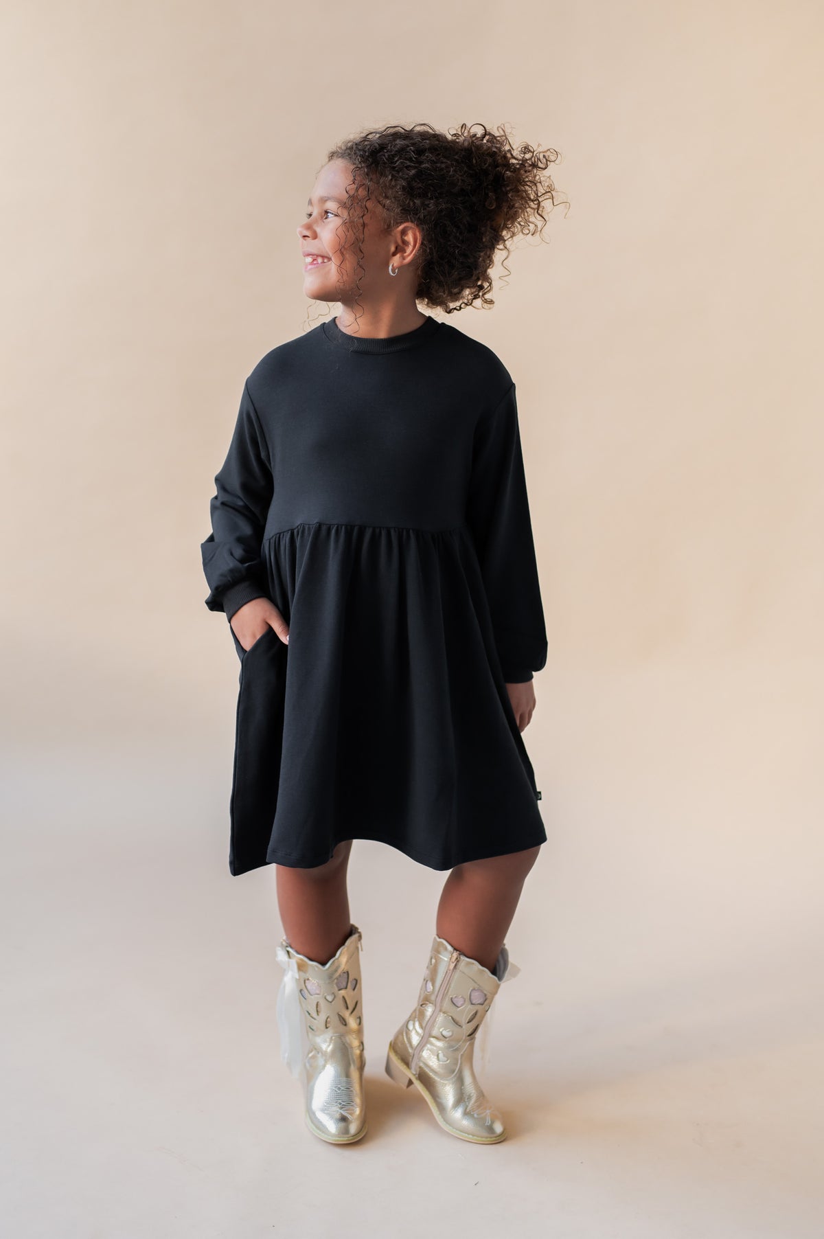Girl posing in Long Sleeve Skater Dress in Midnight color on a beige background