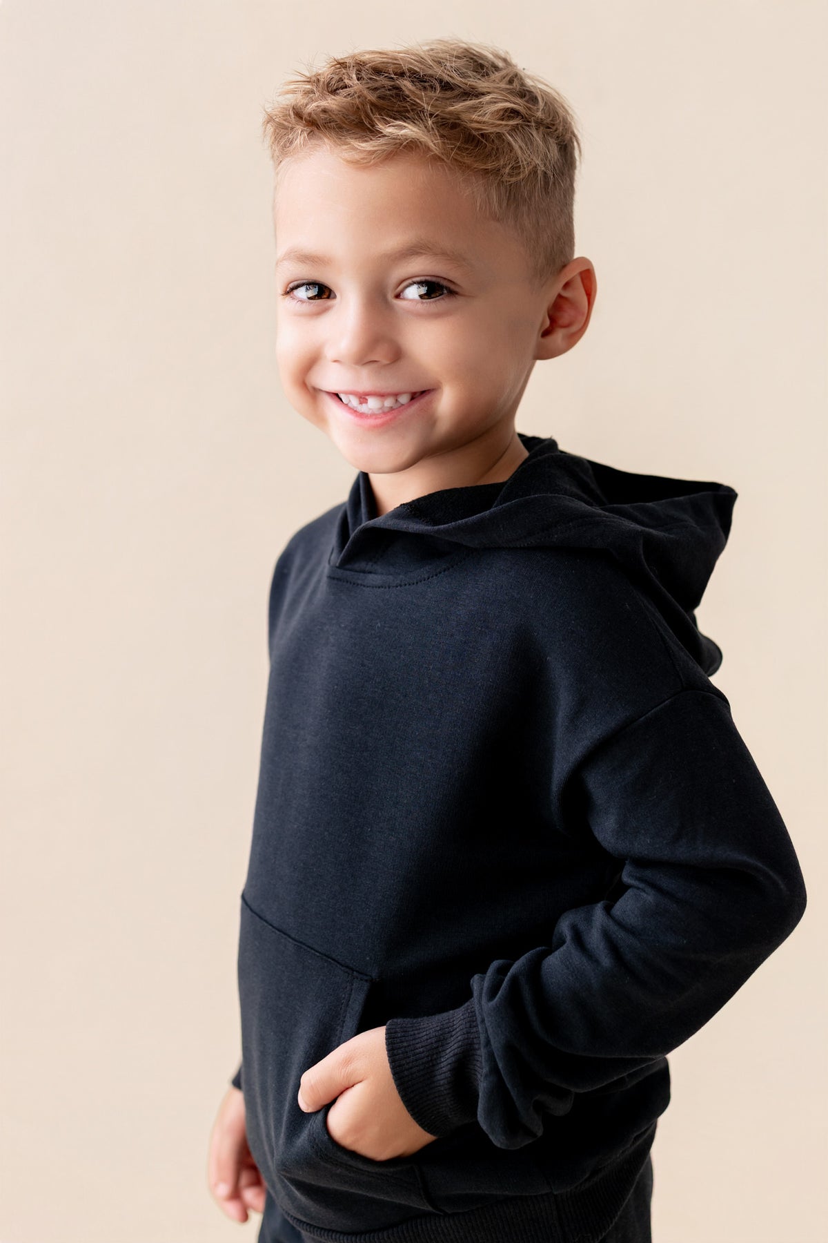 Boy posing wearing Hoodie in Midnight color on a beige background