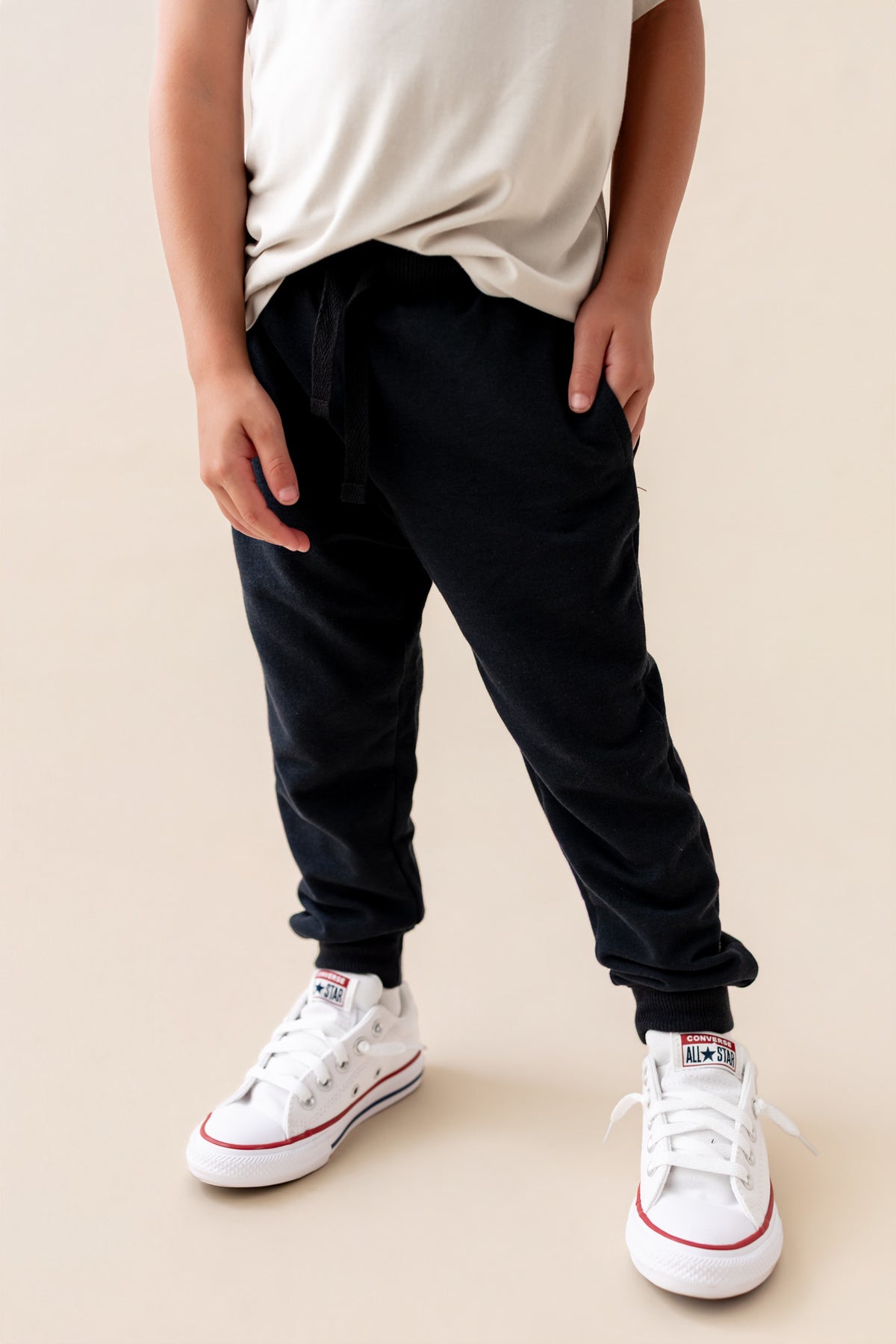 Modal wearing Jogger Pant in Midnight color under white T-shirt and shoes on a beige background