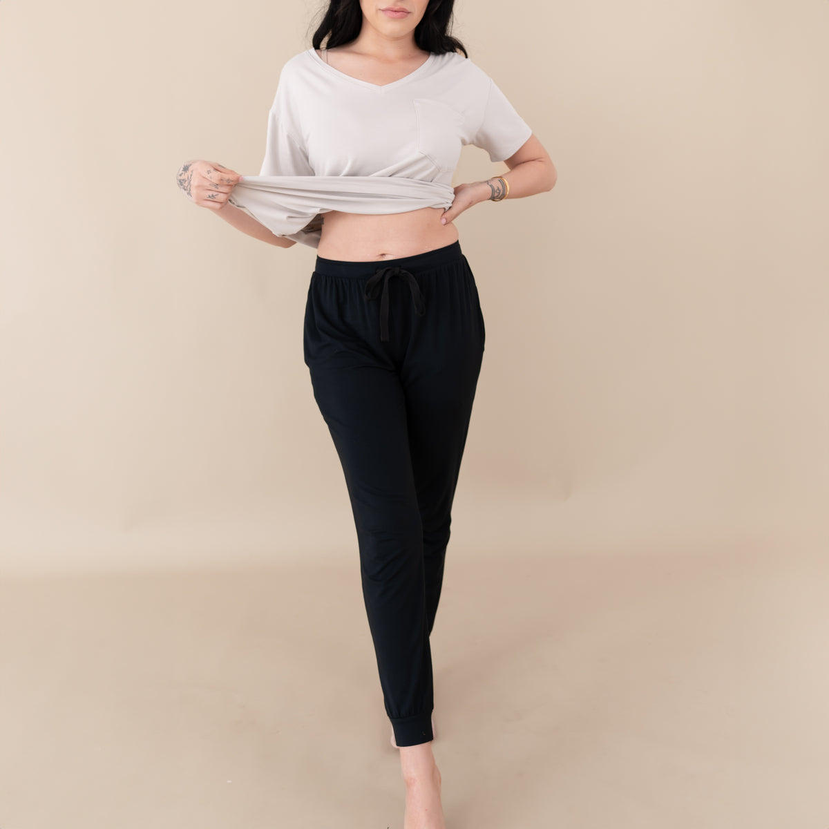 Woman modeling Women's Jogger Pants in Midnight with an oat v-neck with legs slightly crossed