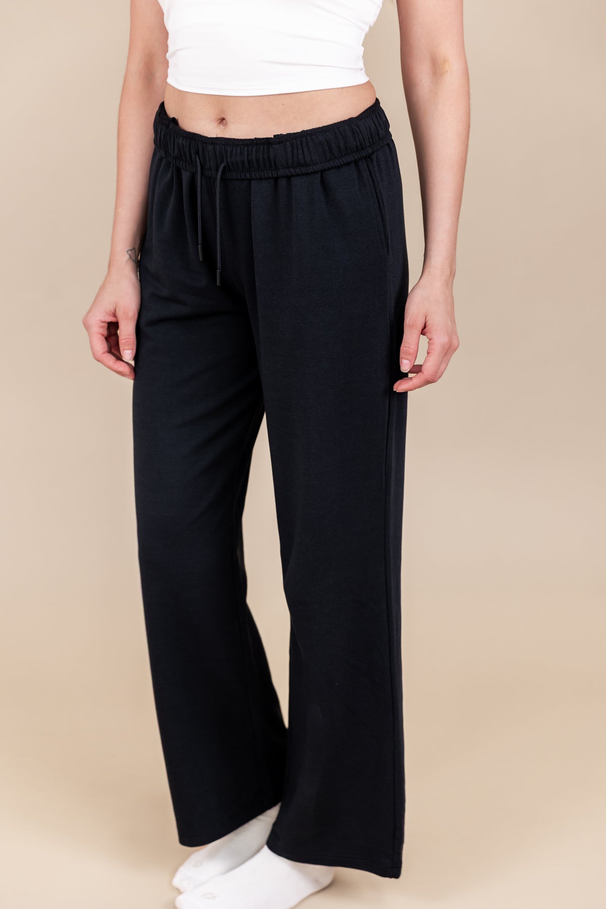 Modal wearing Women's Sweatpants in Midnight color under white flex bra tank and white socks on a beige background