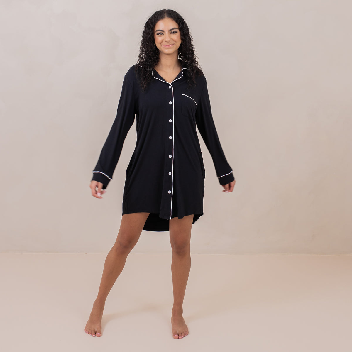 Female standing wearing the Long Sleeve Women’s Nightshirt in Midnight in front of a light taupe backdrop