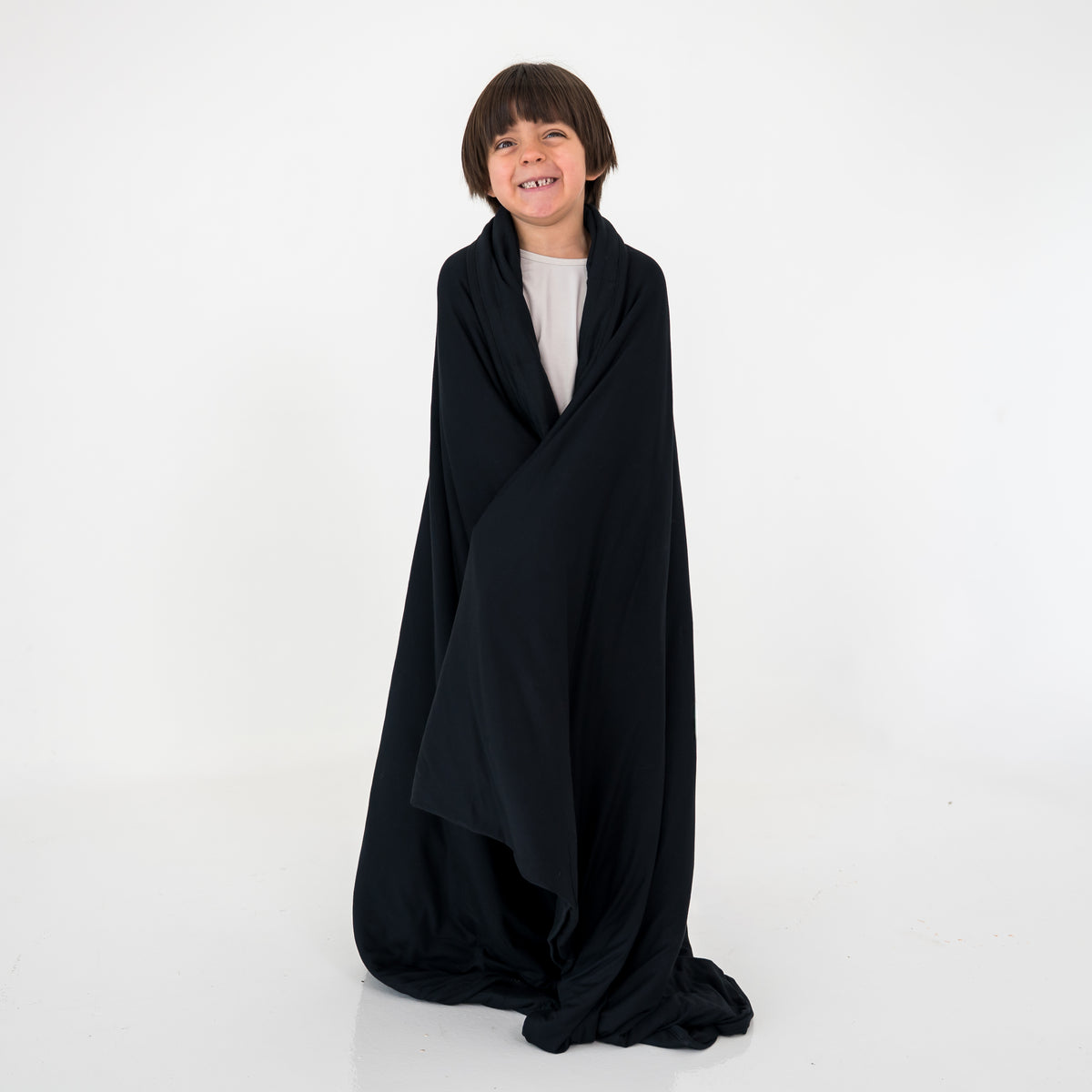 Child wearing a black blanket on a white background
