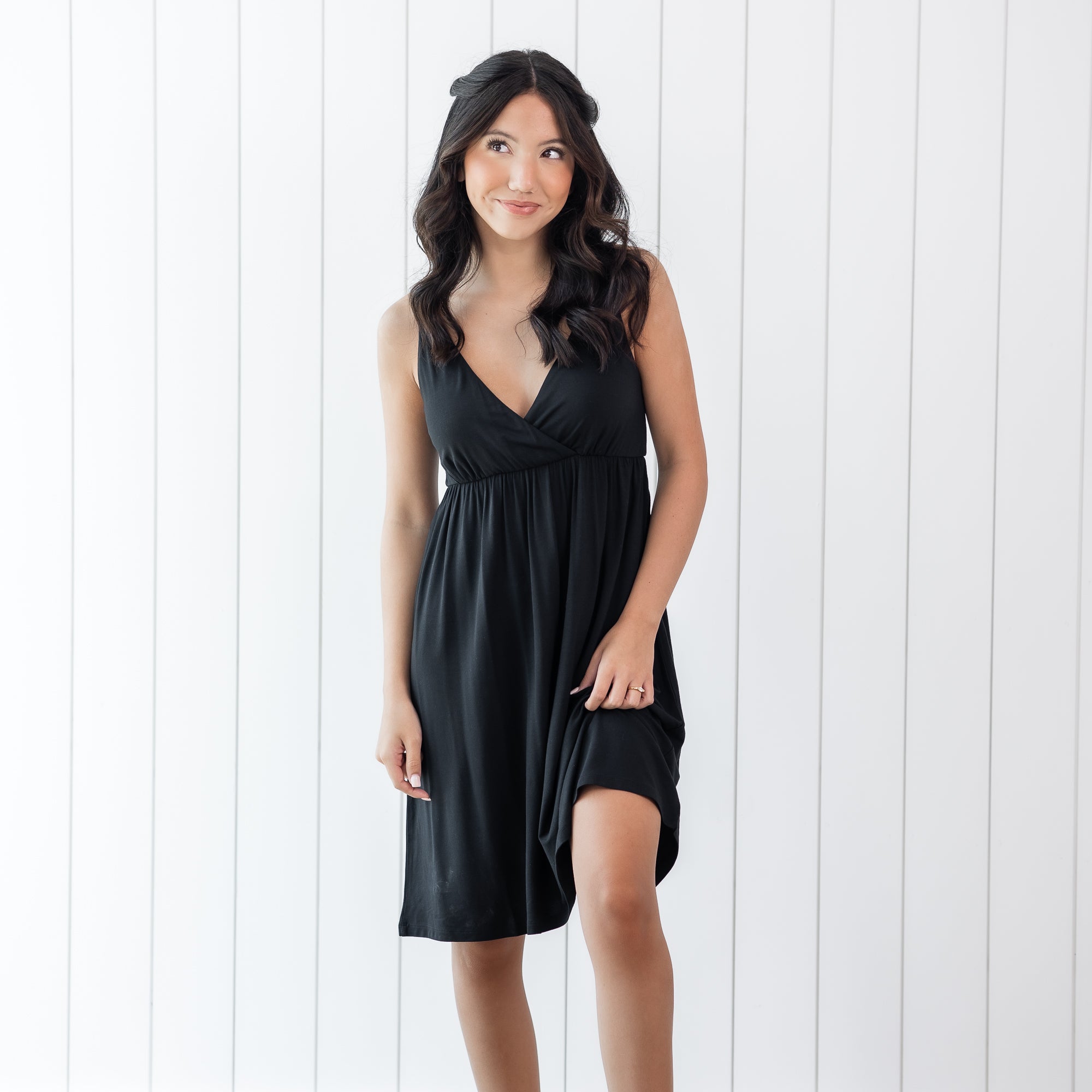 Woman wearing a black nightgown against a white wooden panel background