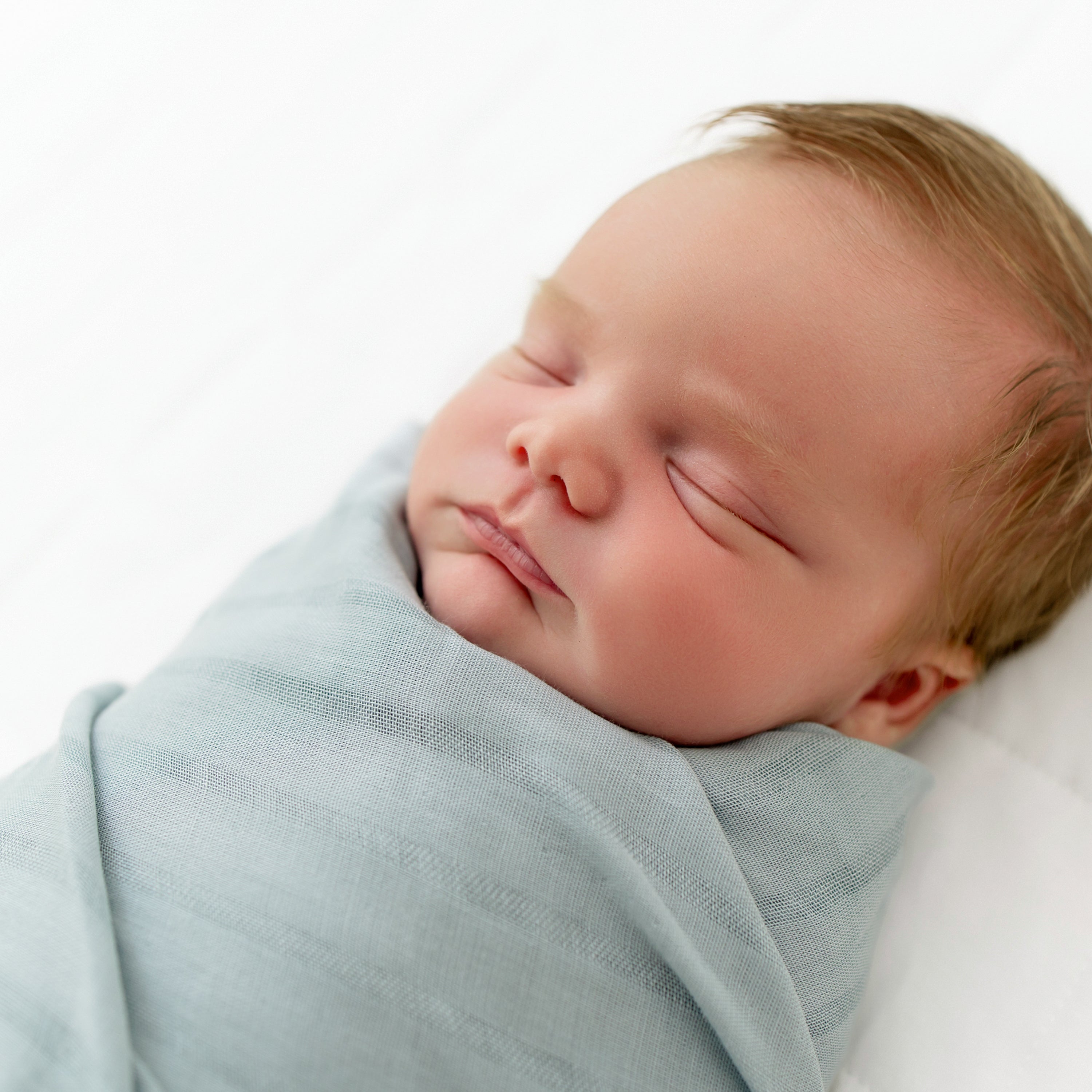 Baby swaddled in Blue Bamboo Muslin Swaddle Blanket with Woven Stripes