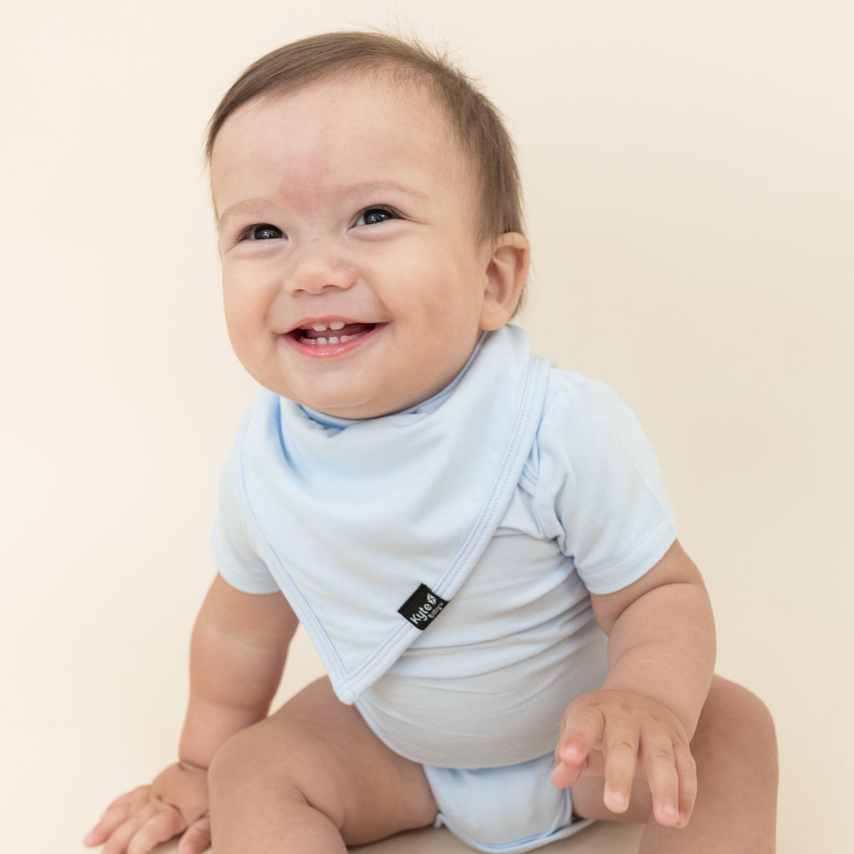Smiling infant wearing the Bib in Mist with matching bodysuit