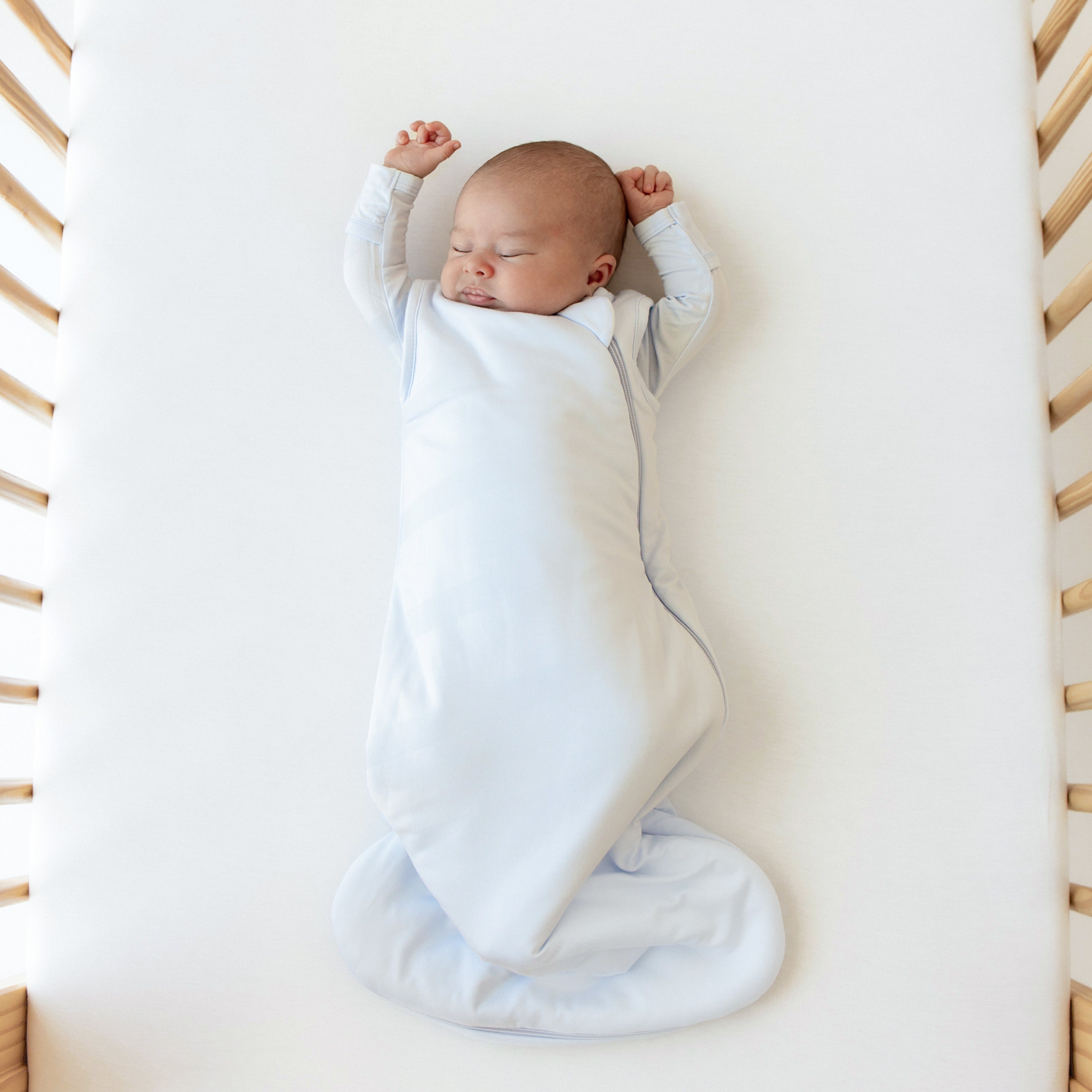 Baby sleeping without the swaddling band of the Kyte Baby Sleep Bag Swaddler in Mist 1.0