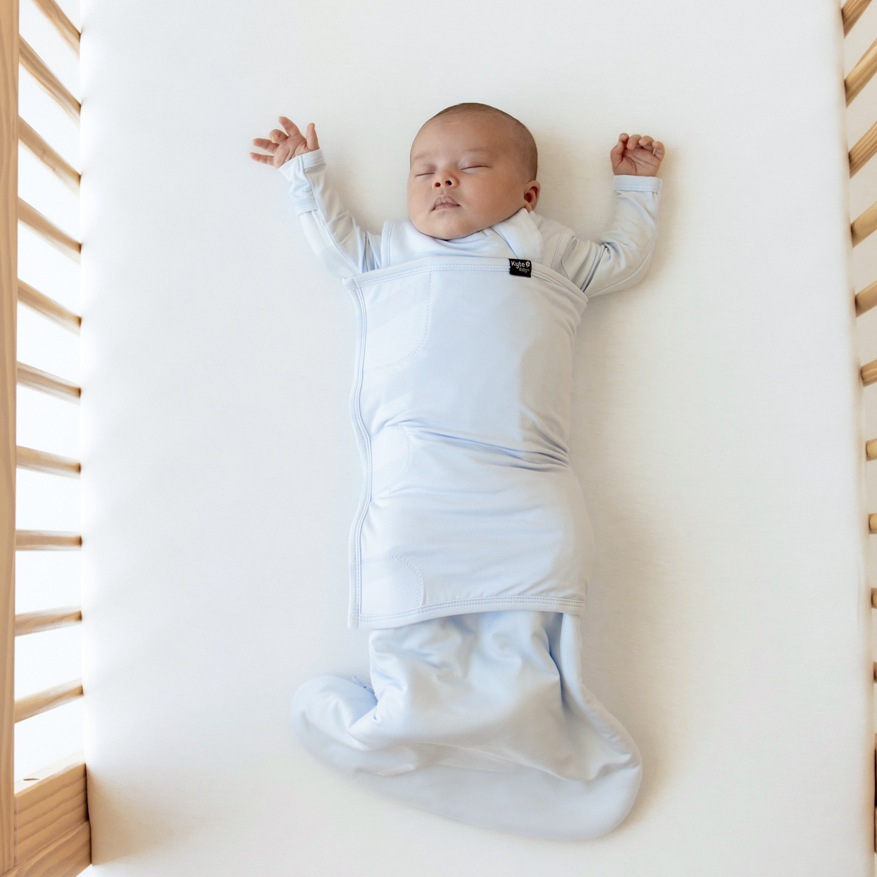 Baby sleeping with both arms out Kyte Baby Sleep Bag Swaddler in Mist 1.0