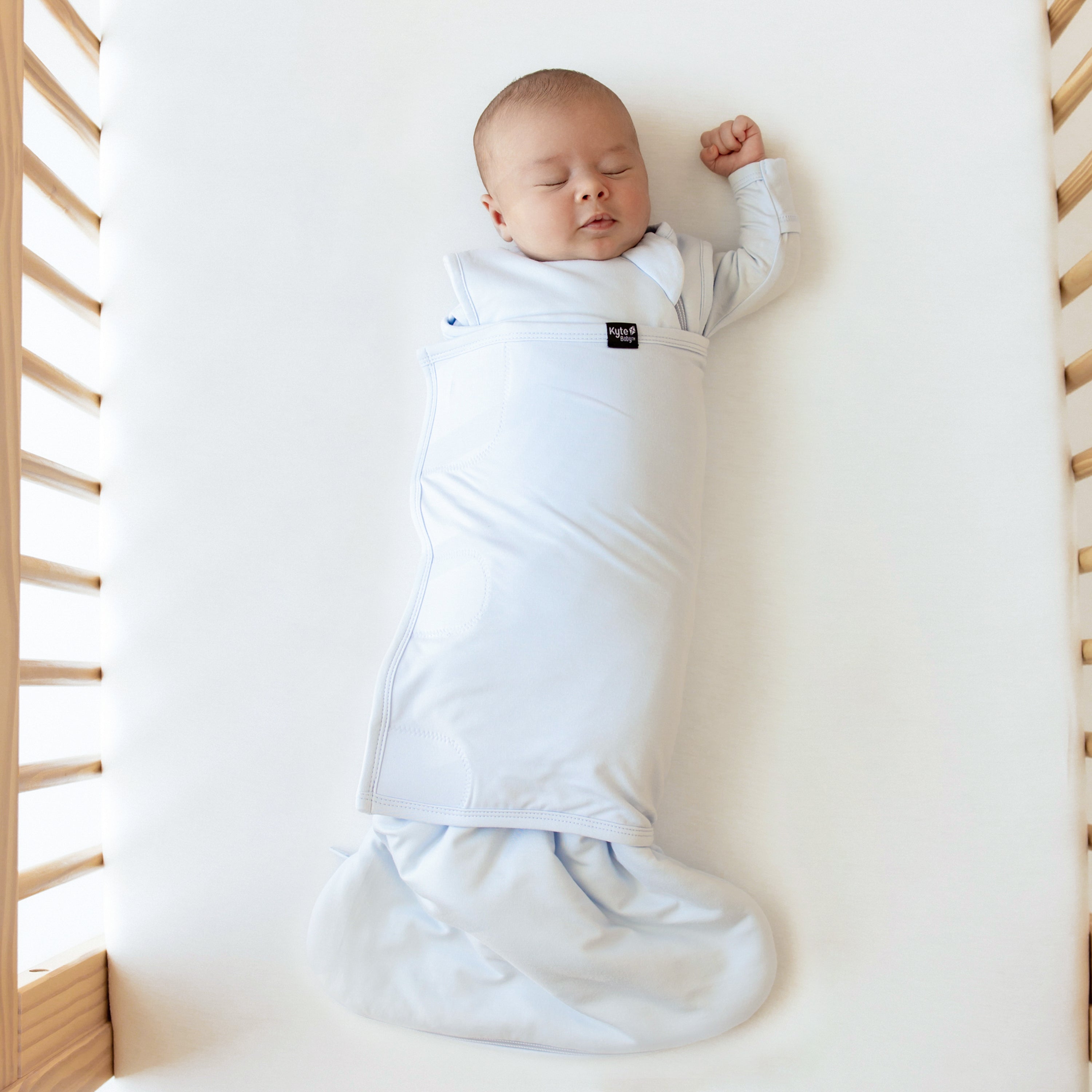Baby sleeping with one arm out Kyte Baby Sleep Bag Swaddler in Mist 1.0