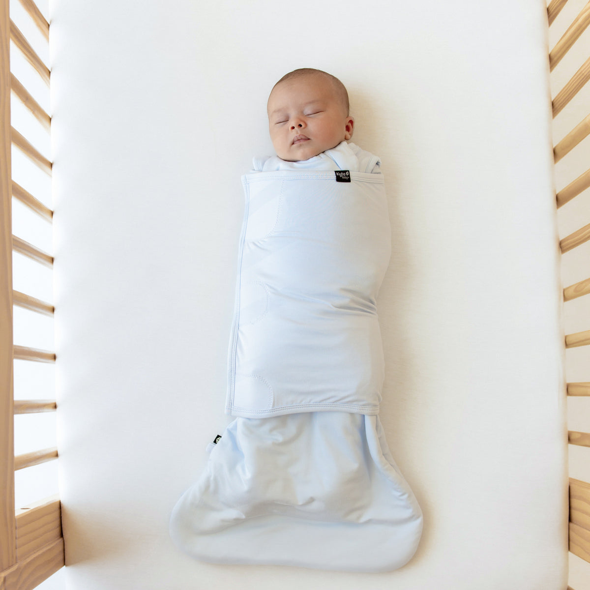 Baby sleeping with both arms in Kyte Baby Sleep Bag Swaddler in Mist 1.0