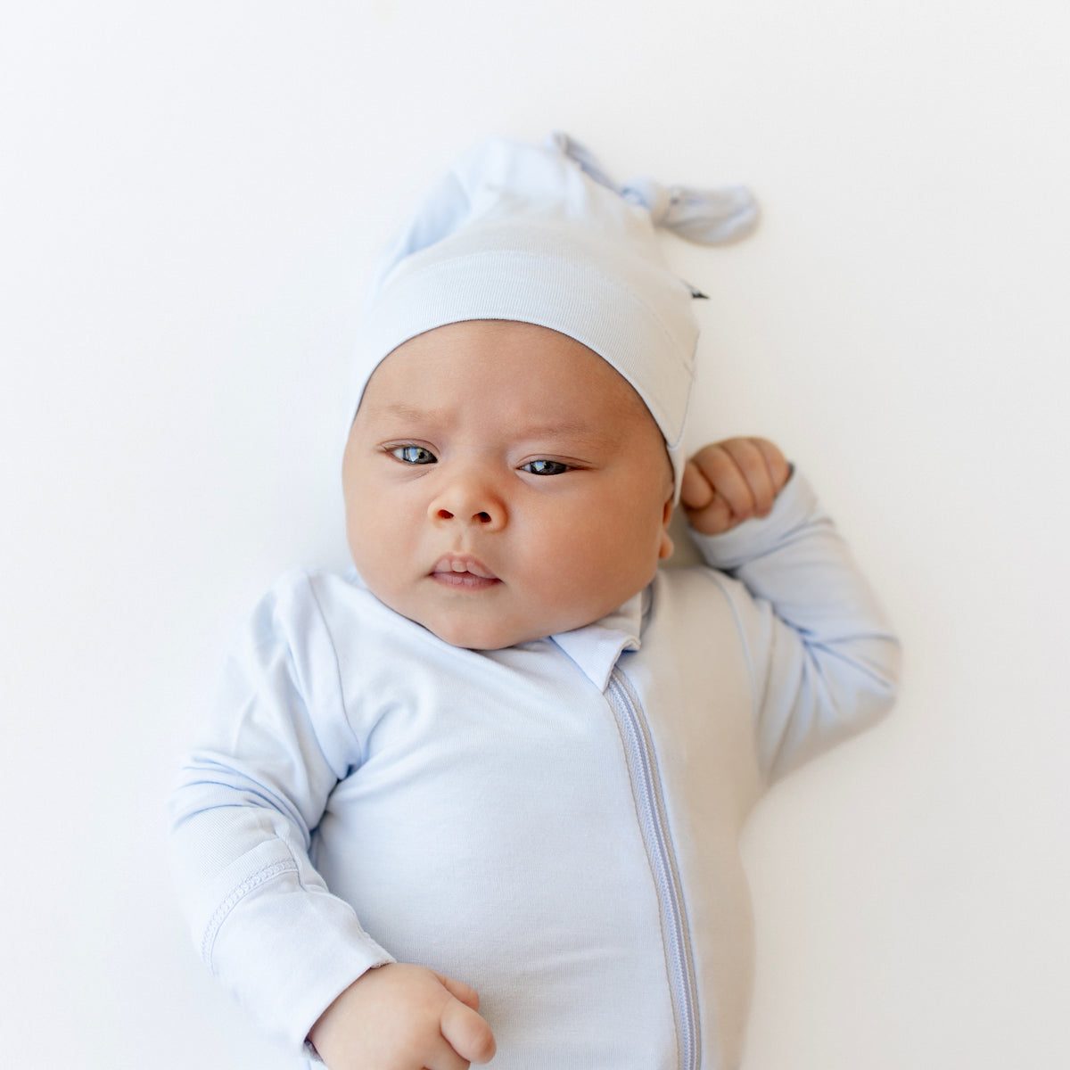 Close up of infant wearing Zippered Footie in Mist paired with the Knotted Cap in Mist