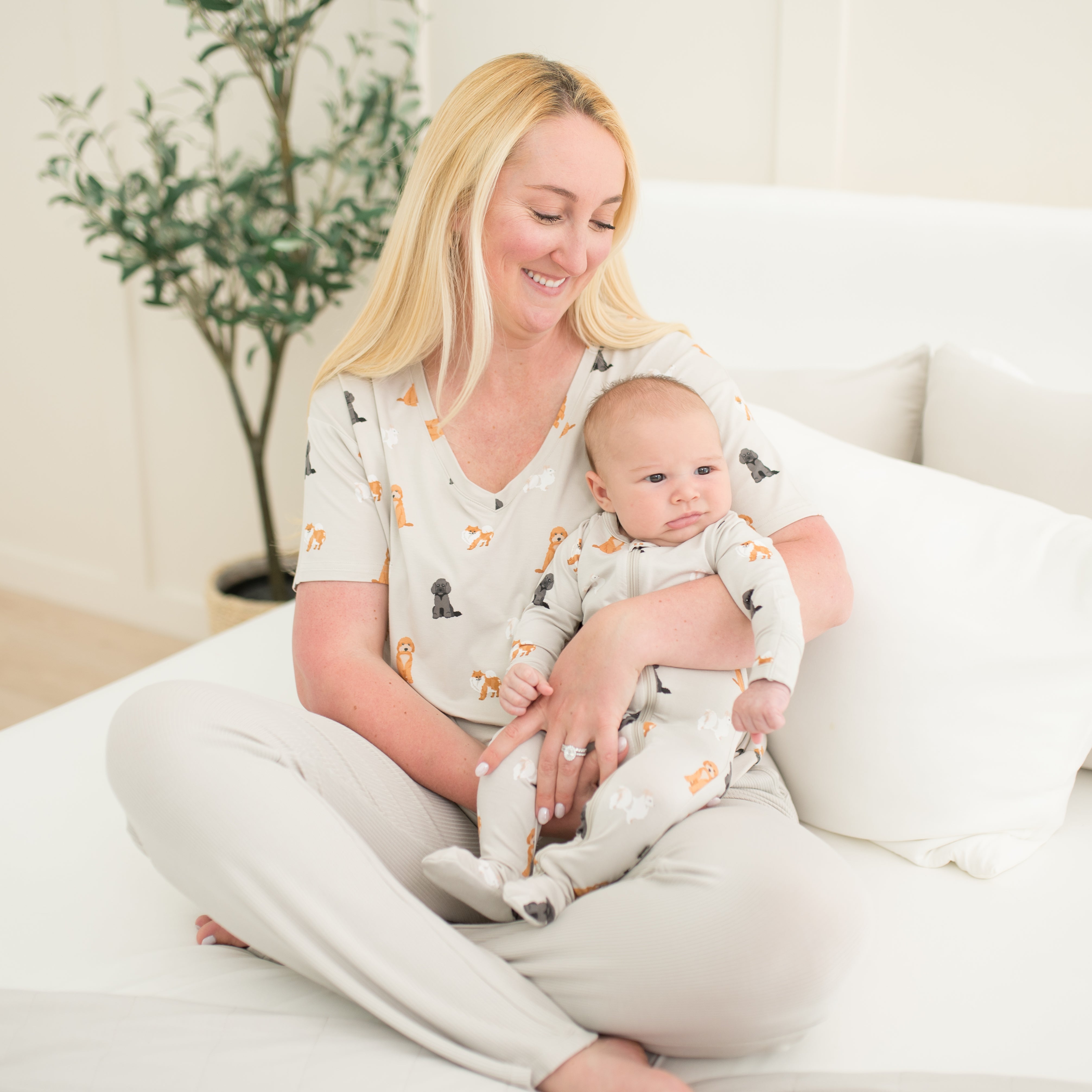 Mom wearing Women’s Relaxed Fit V-Neck in Fluffy Dog holding baby wearing matching Zippered Footie