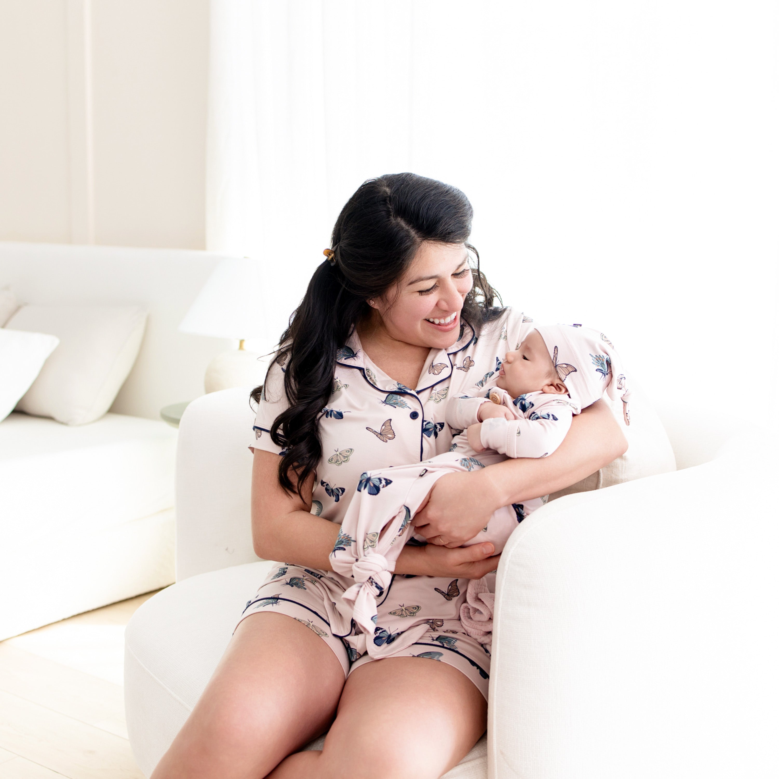 Mom wearing Women’s Short Sleeve Pajama Set in Blush Butterfly holding baby in matching knotted gown set