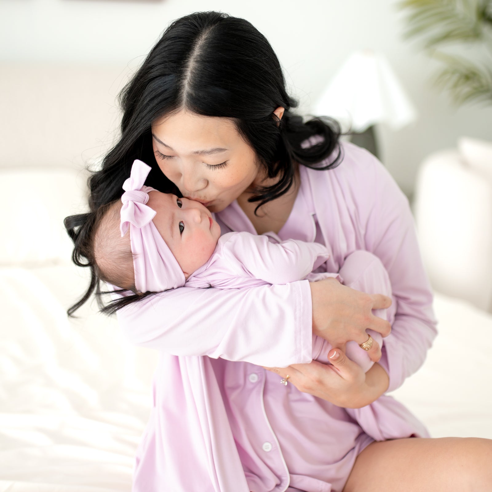 Woman in a pink robe holding a baby wrapped in a pink blanket, both wearing matching headbands.