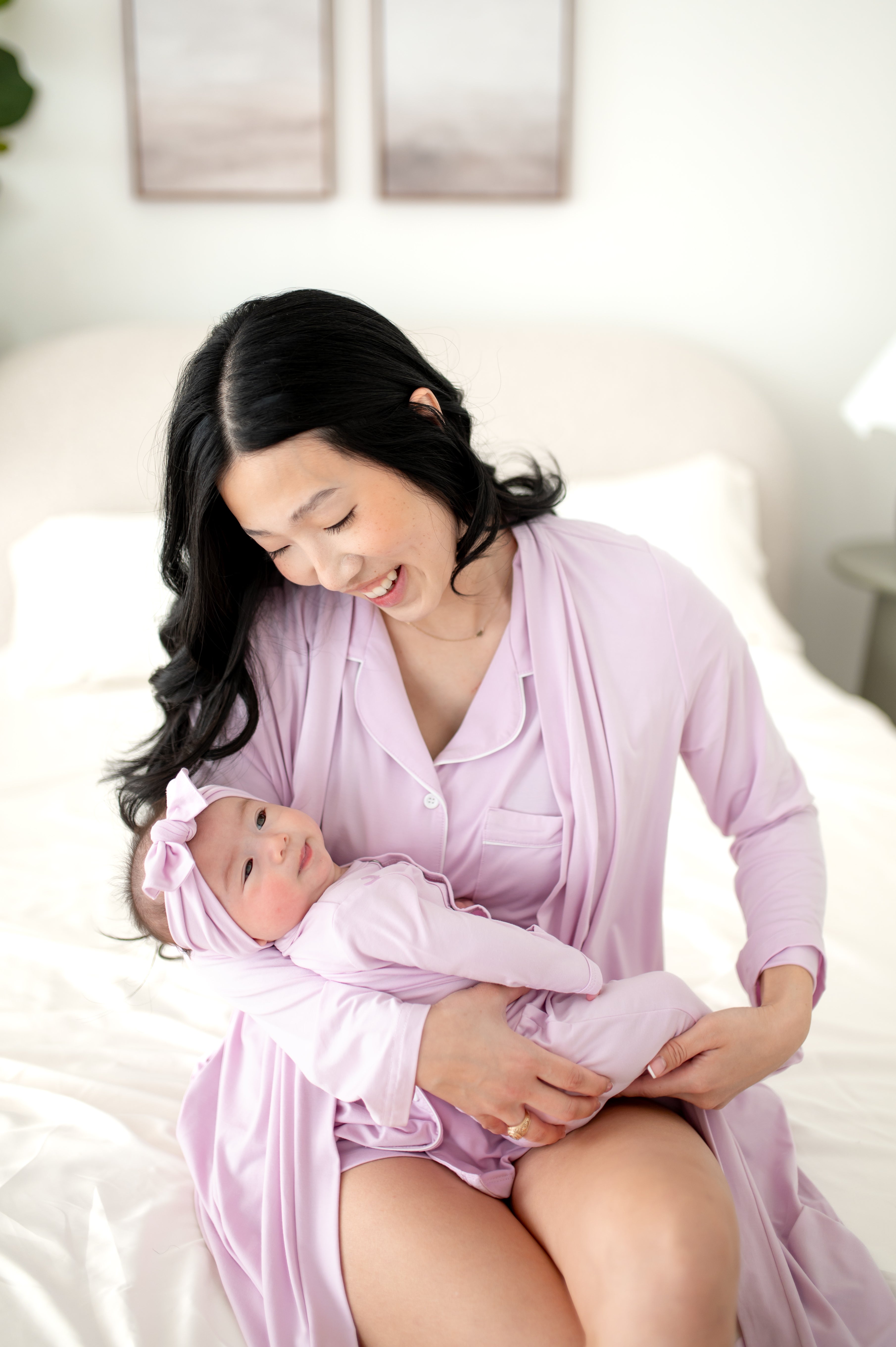 Woman wearing a light purple PJ set and robe holding baby in matching outfit