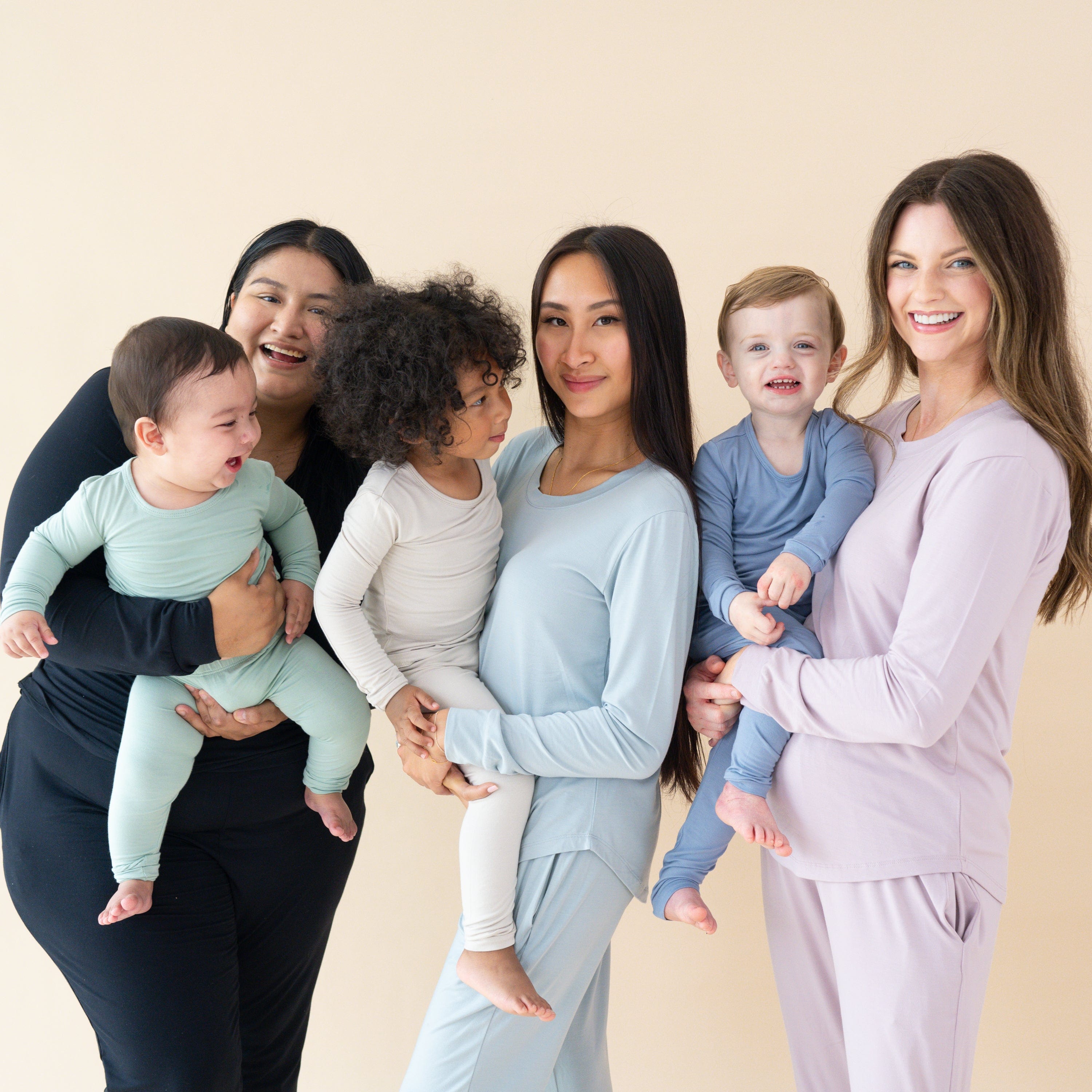 Moms holding toddlers wearing Kyte Baby pajamas