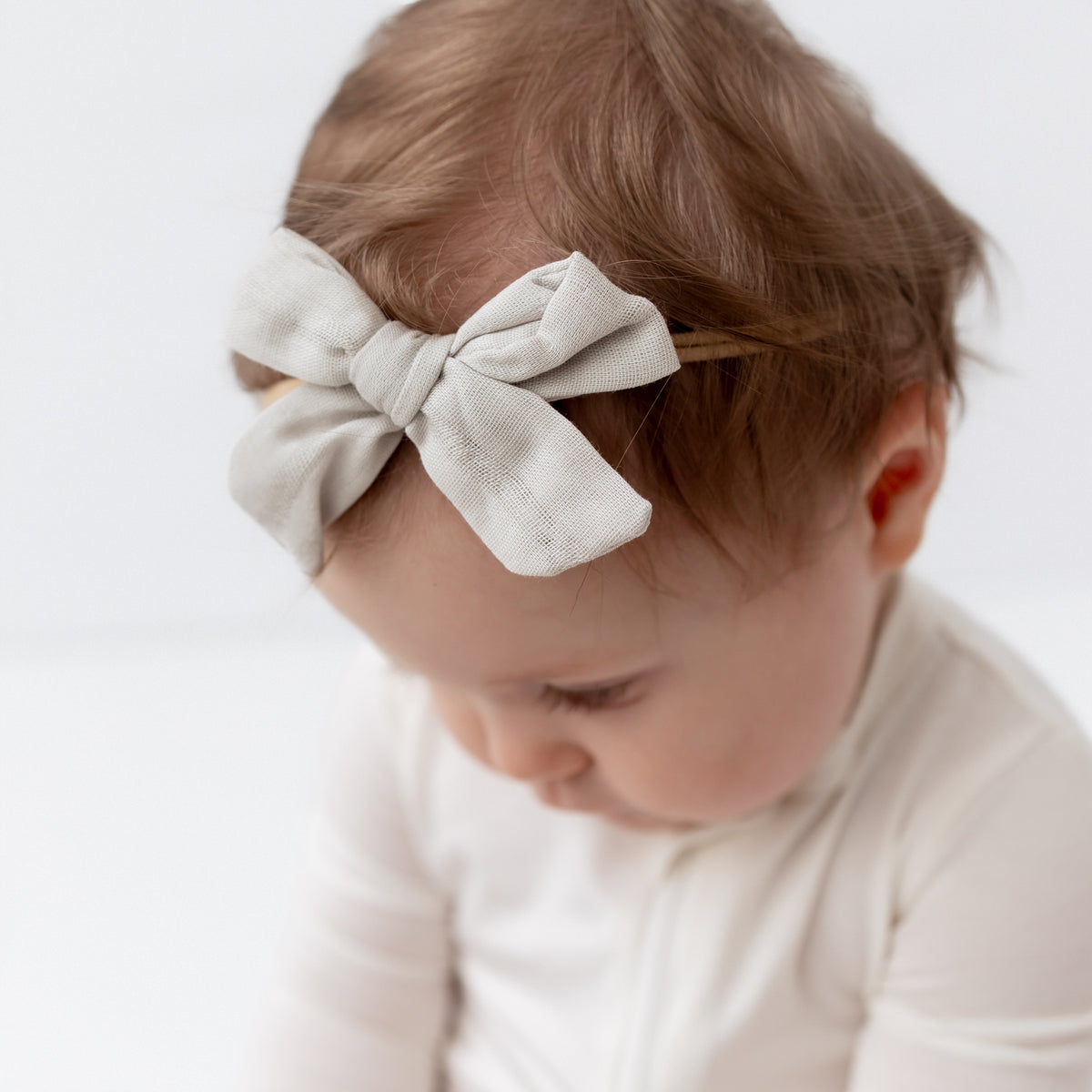 Close up of Bamboo Muslin Medium Bow in Oat while on baby's head