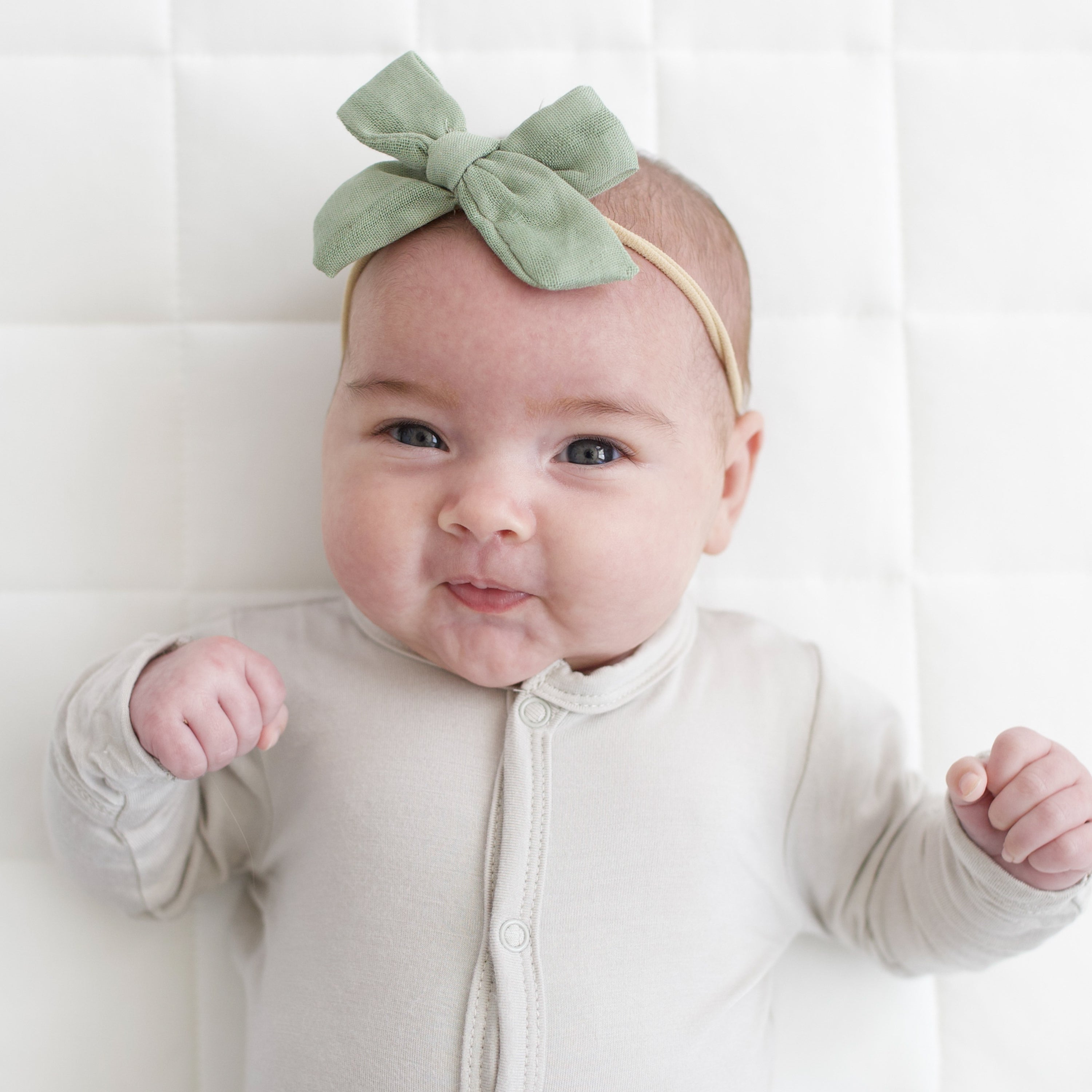 Baby wearing Medium Bamboo Muslin Bow in Jojoba green