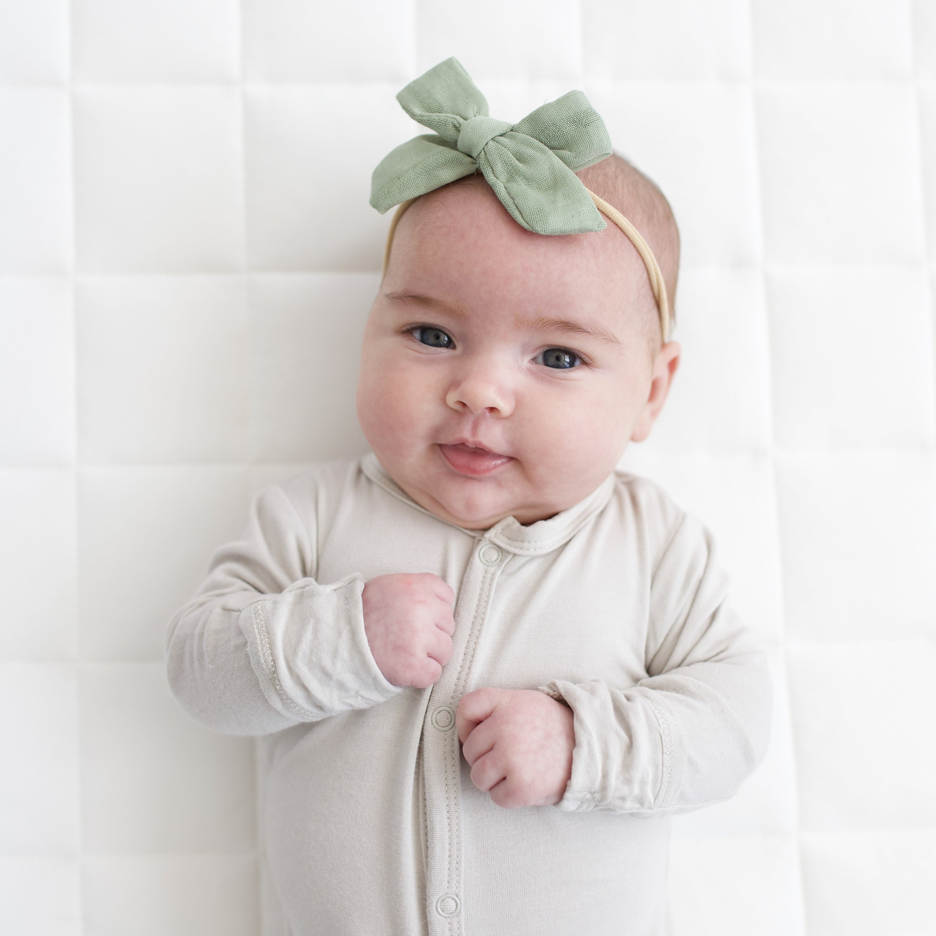 Baby wearing Medium Bamboo Muslin Bow in Jojoba with Neutral Pajamas